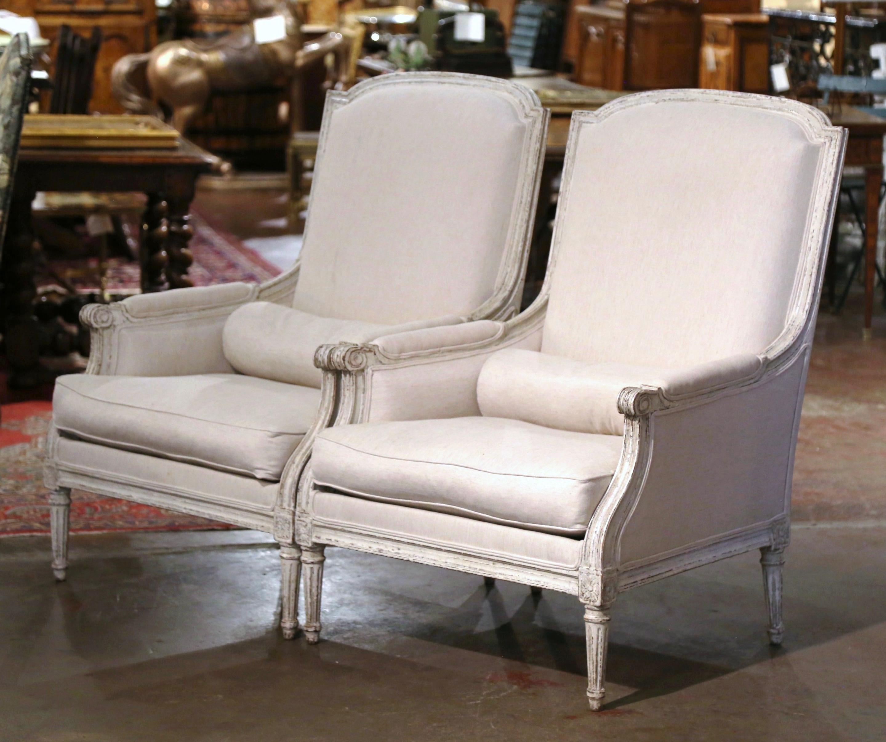 These elegant antique armchairs were created in France, circa 1880. The large fauteuils stand on fluted and tapered legs decorated with square rosette medallions at the shoulders; each chair features a tall arched and curved back dressed with