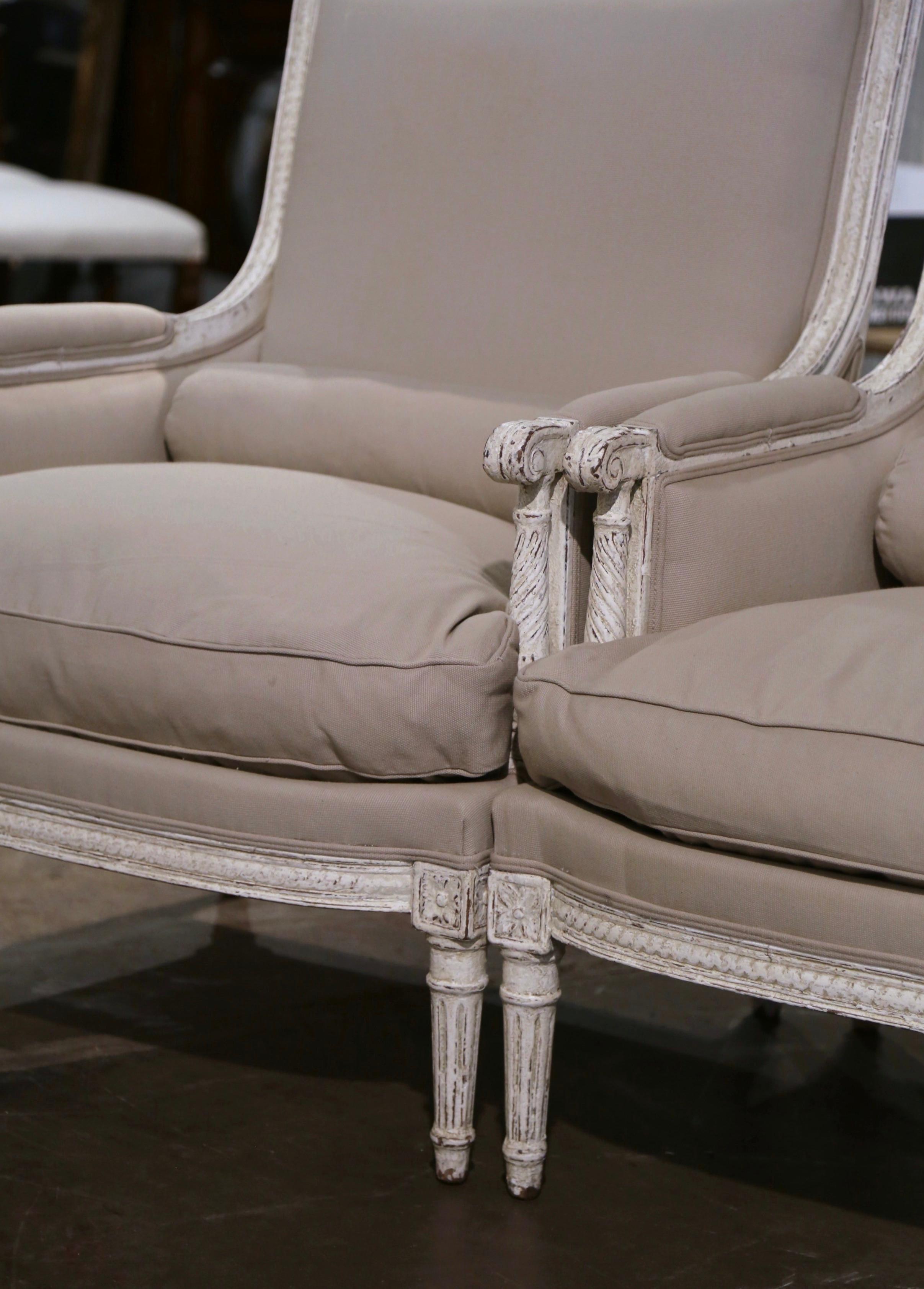Cette élégante paire de fauteuils anciens a été créée en France, vers 1880. Les grands fauteuils à dossier haut et droit reposent sur des pieds avant fuselés et cannelés, décorés de médaillons carrés aux épaules, sur un tablier à bombe et des pieds