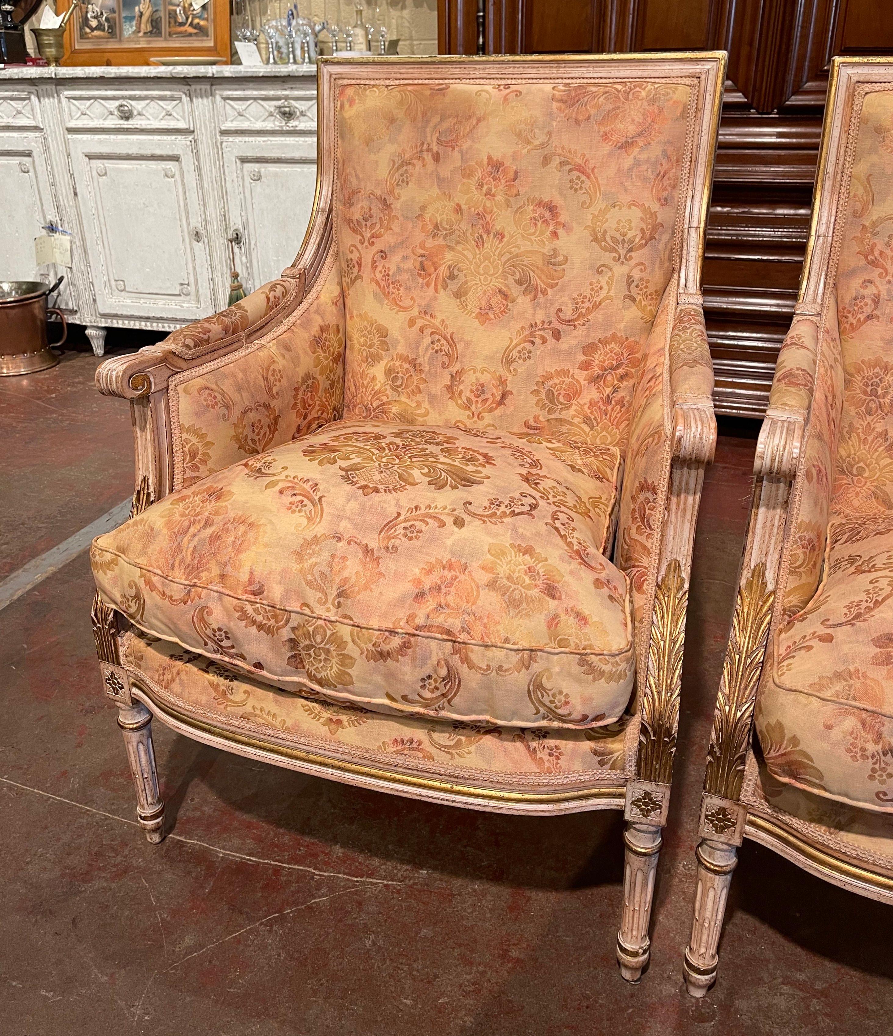 Complete your formal living room or den with this elegant pair of antique bergeres. Created in France, circa 1890, the Classic chairs Stand on tapered and fluted legs embellished with floral medallions at the shoulders. Each fauteuil features a wide