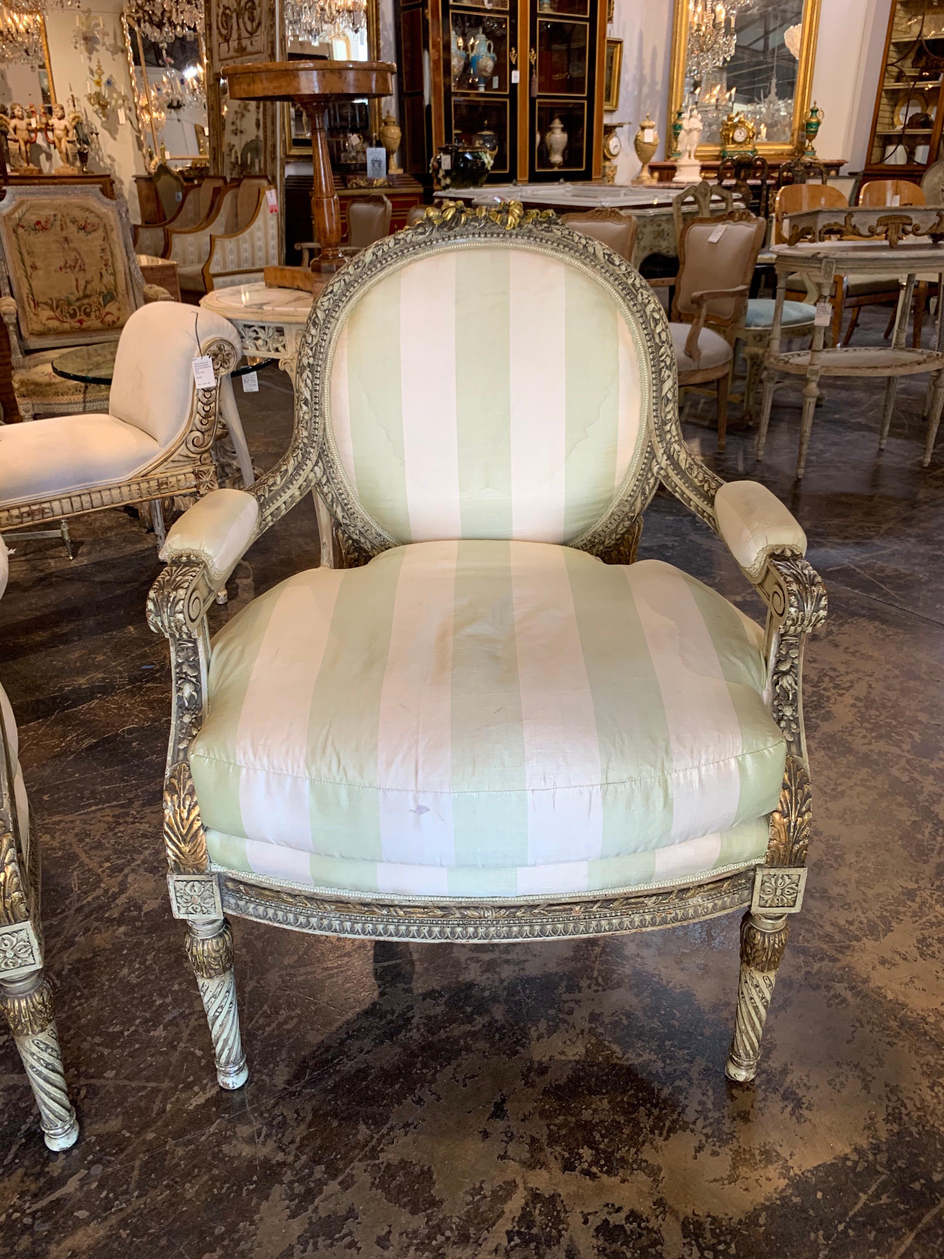 Beautiful large scale 19th century French Louis XVI Fauteuils upholstered in a pale green and crème colored silk. The wood frame has very fine carvings with touches of gold gilt. Very comfortable chairs as well! Note: There are a few stains on the