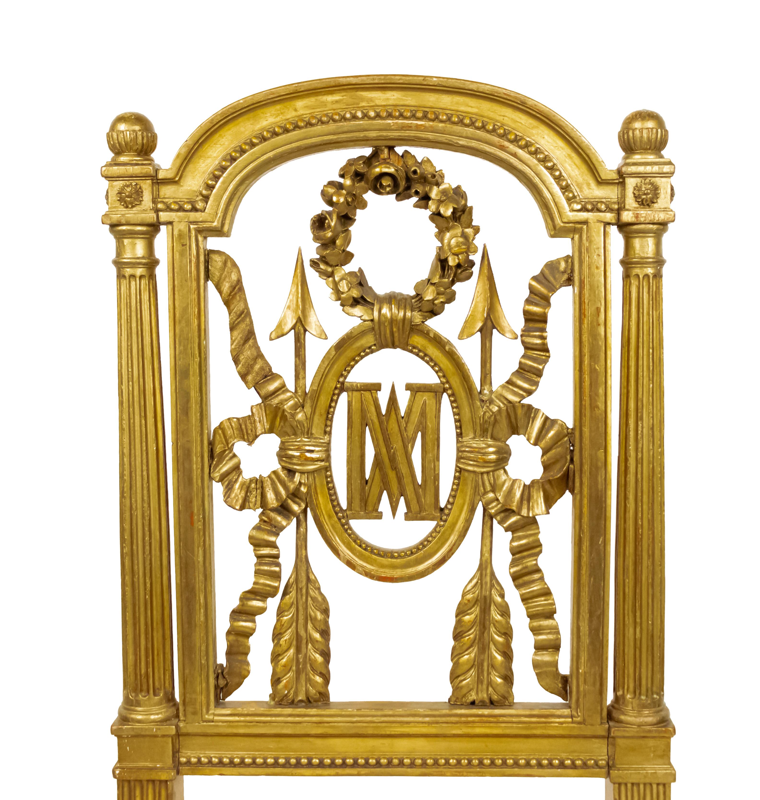 Zwei vergoldete französische Beistellstühle im Louis XVI-Stil (19. Jh.) mit geschnitzter Rückenlehne mit Kranz und Pfeil sowie den Initialen MA (Marie Antoinette) und zeitgenössischer, weißer, mehrfarbiger, geometrischer Polsterung.
 