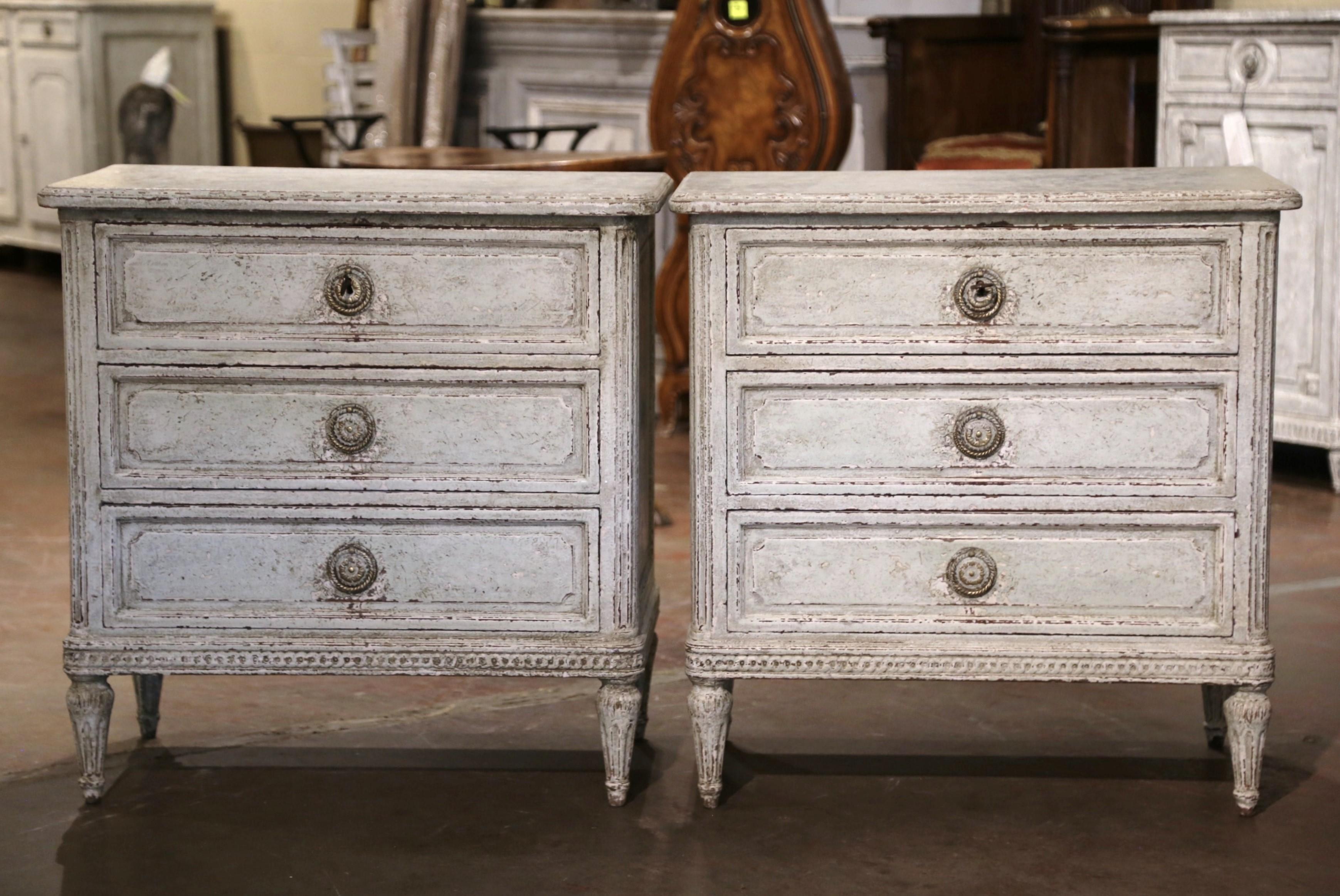Complete your bedroom with this elegant pair of antique hand painted bedside cabinets; crafted in France, circa 1880, each commode stands on tapered and fluted legs over a straight apron decorated with geometric motif. Each chest features three