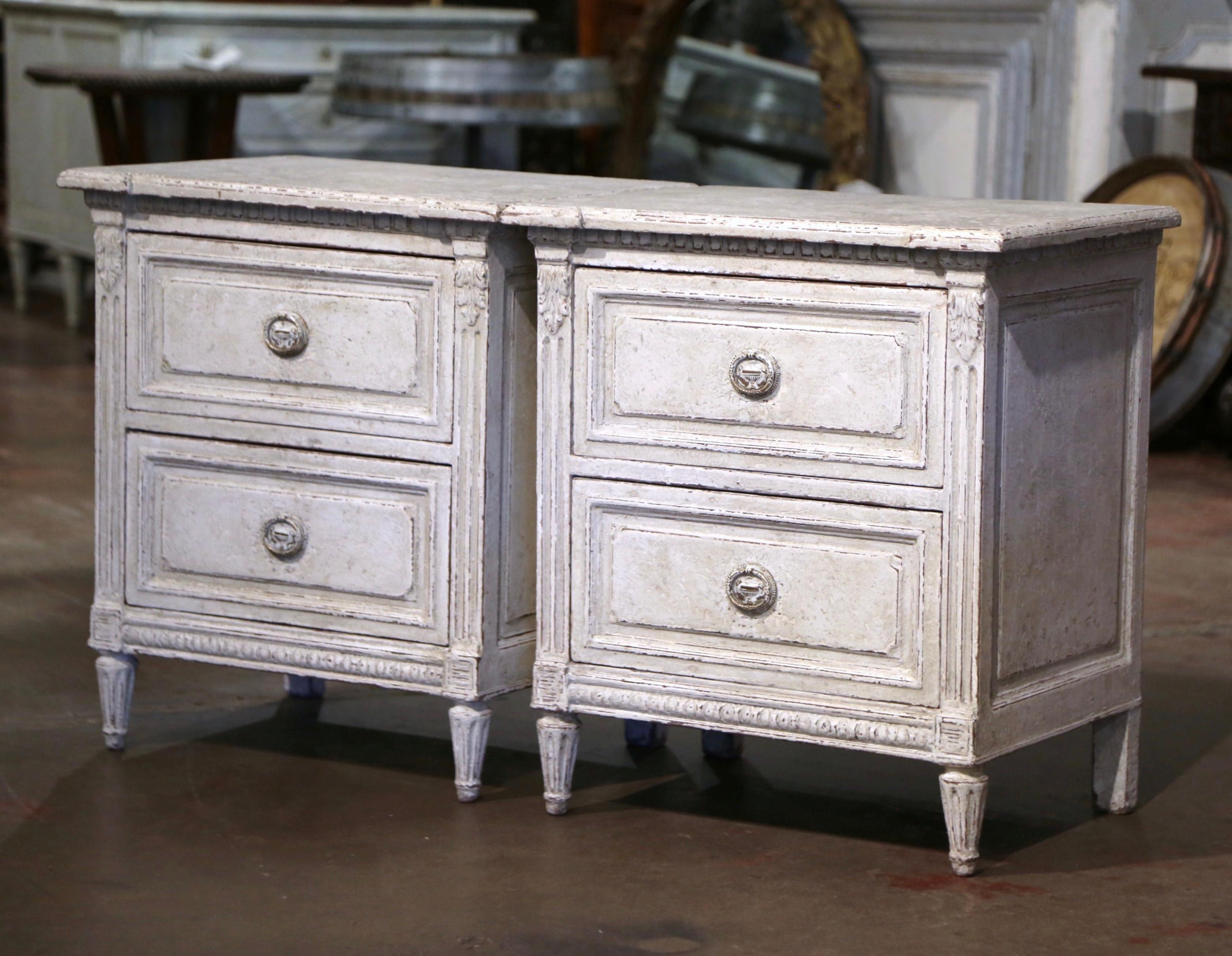 Complete your bedroom with this elegant pair of antique painted bedside cabinets. Crafted in France circa 1880, each commode stands on tapered and fluted legs over a carved plinth apron. The chest with side spline columns and acanthus leaf motifs,