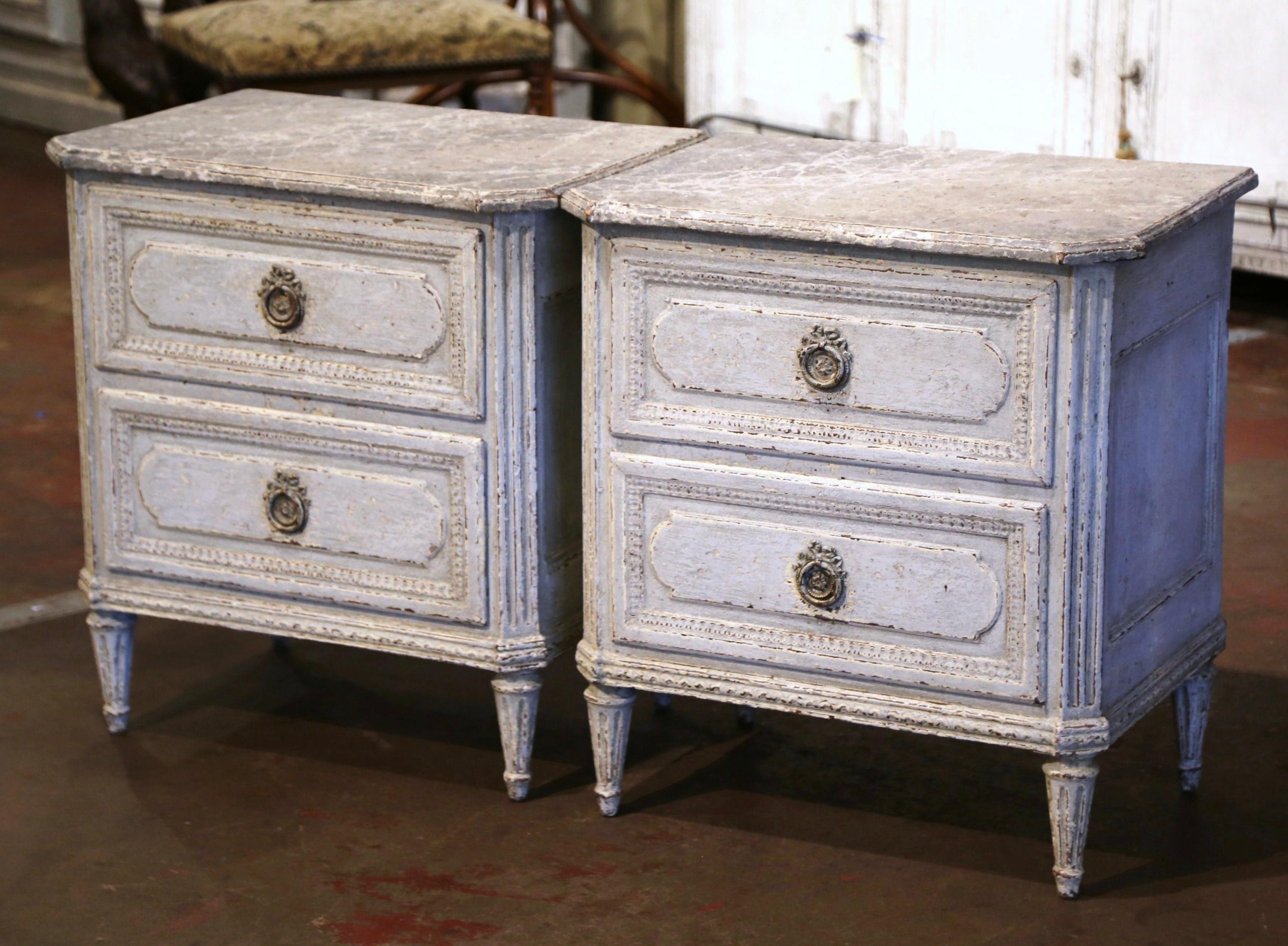 Complete your bedroom with this elegant pair of antique two-tone painted bedside cabinets; crafted in France, circa 1880, each commode stands on tapered fluted legs over side cut spline columns, and decorated with a carved plinth apron. The chest