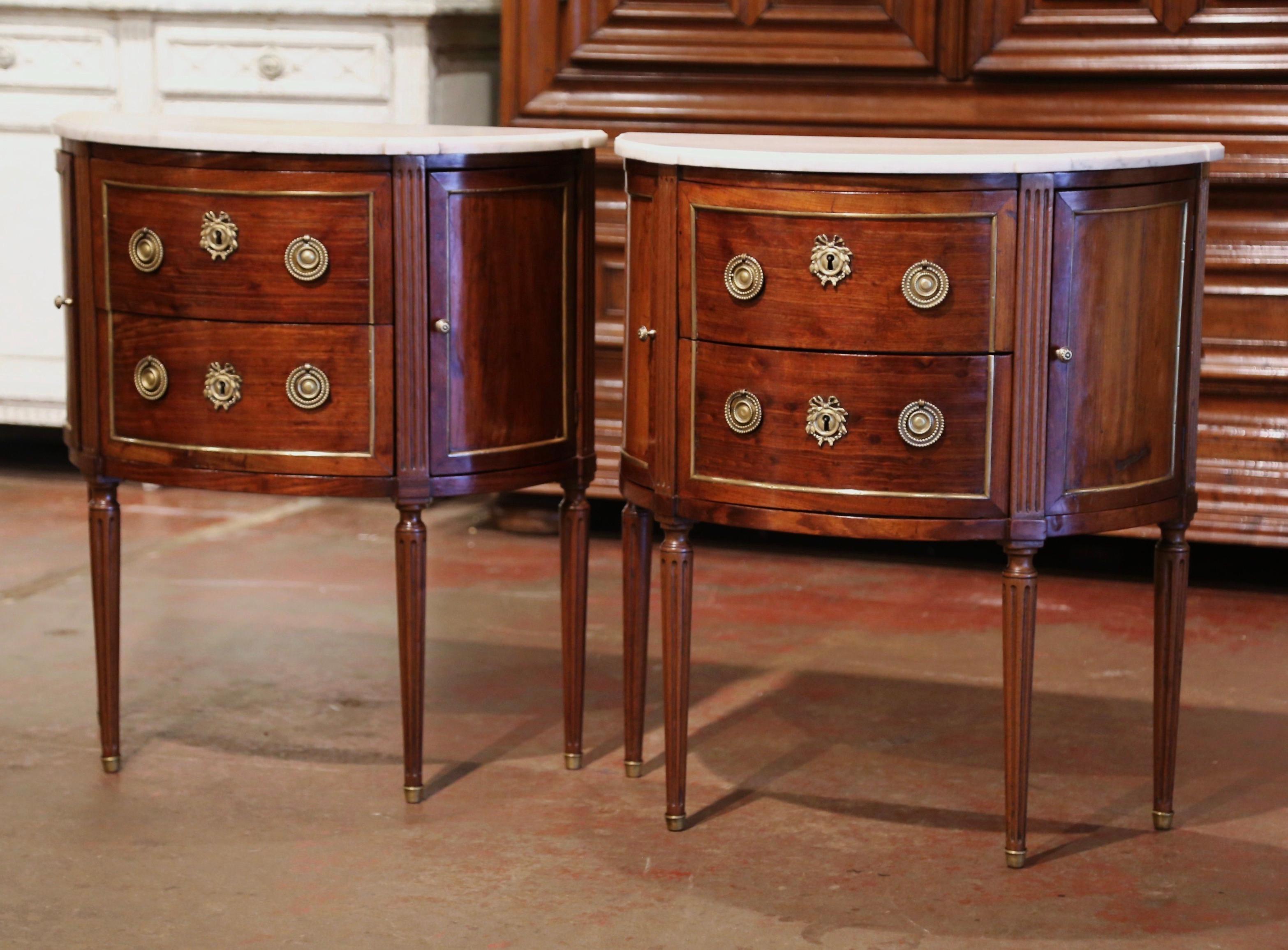 Place this elegant pair of chests on either side of a king side bed and use them as nightstands. Crafted in Paris, France circa 1860, each cabinet shaped a half moon stands on fluted legs ending with brass feet. The commode features two bowed