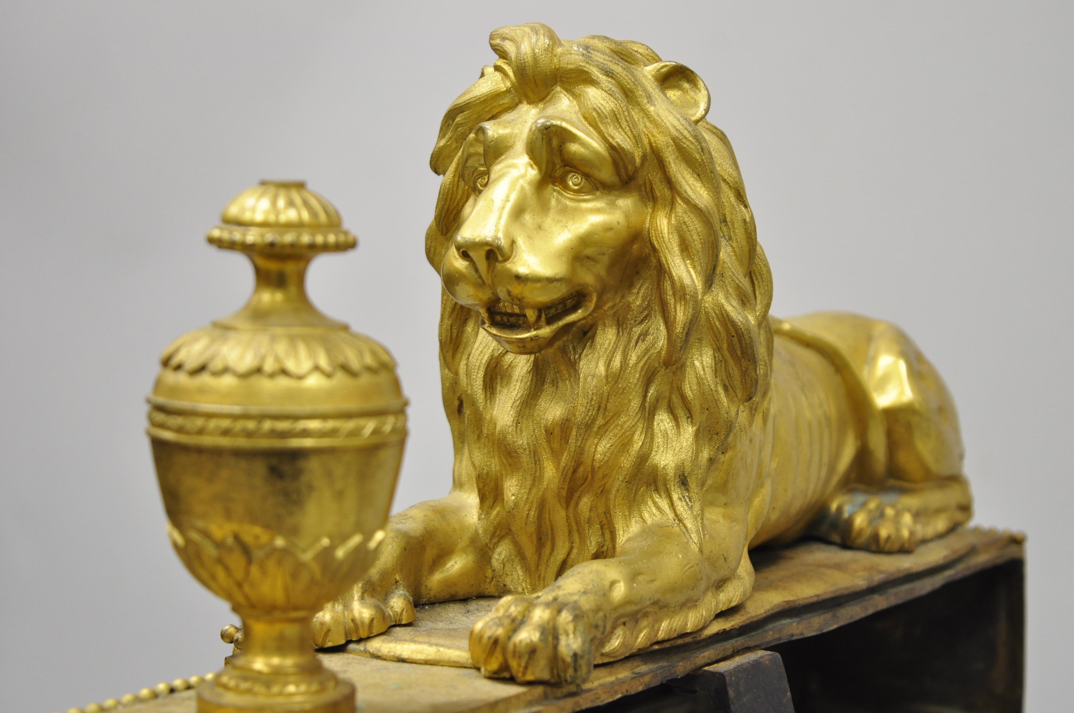 Pair of 19th century French Louis XVI neoclassical gilt bronze lion chenets. Listing includes stunning cast bronze resting lions, gold gilt finish, urn finials, drape accents, stamped 
