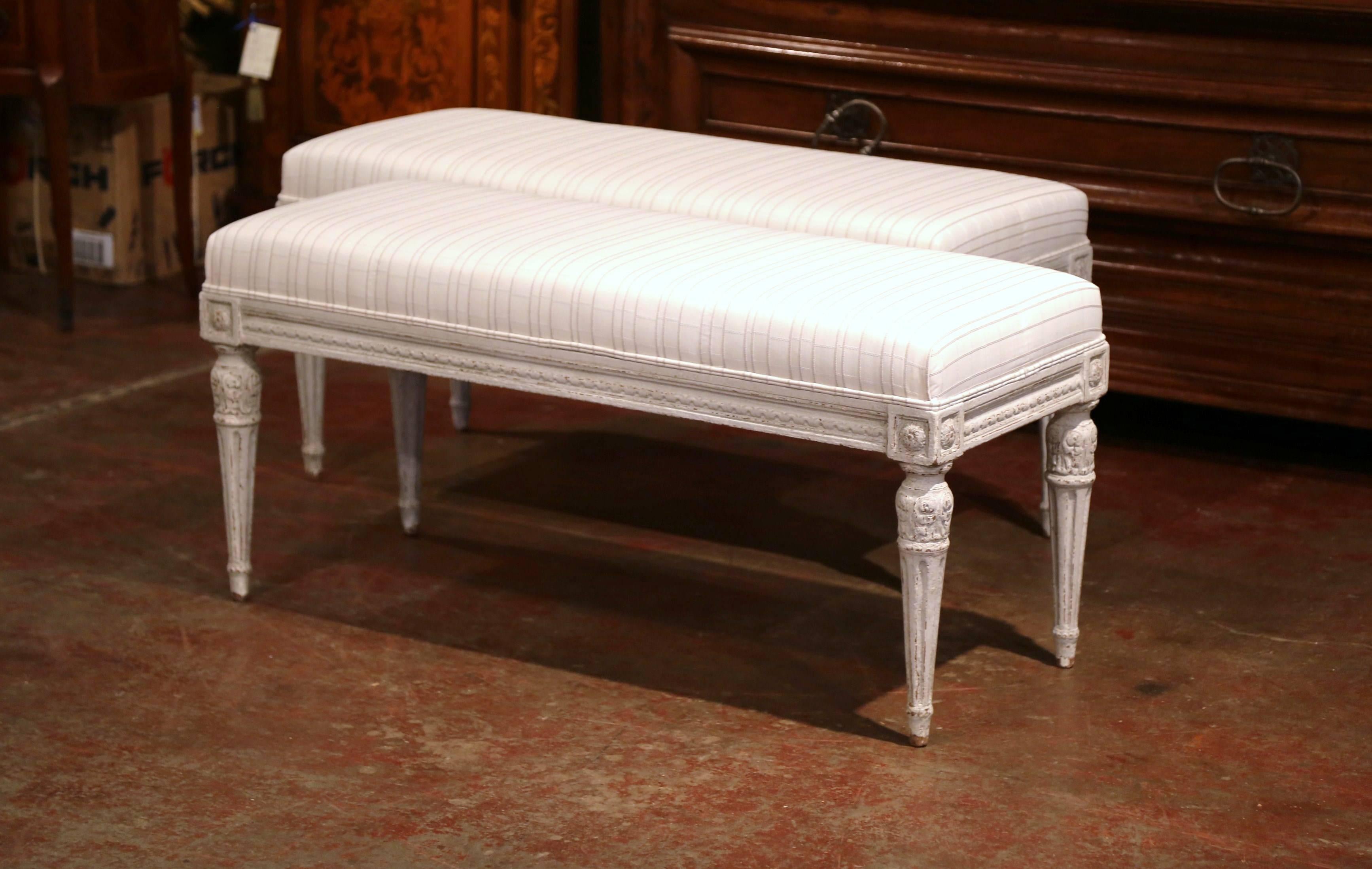 Complete your entryway or living room or bedroom with this pair of antique grey painted benches from France, circa 1890. Rectangular in shape, these pieces feature a carved design around the apron including flower medallions and four fluted legs.