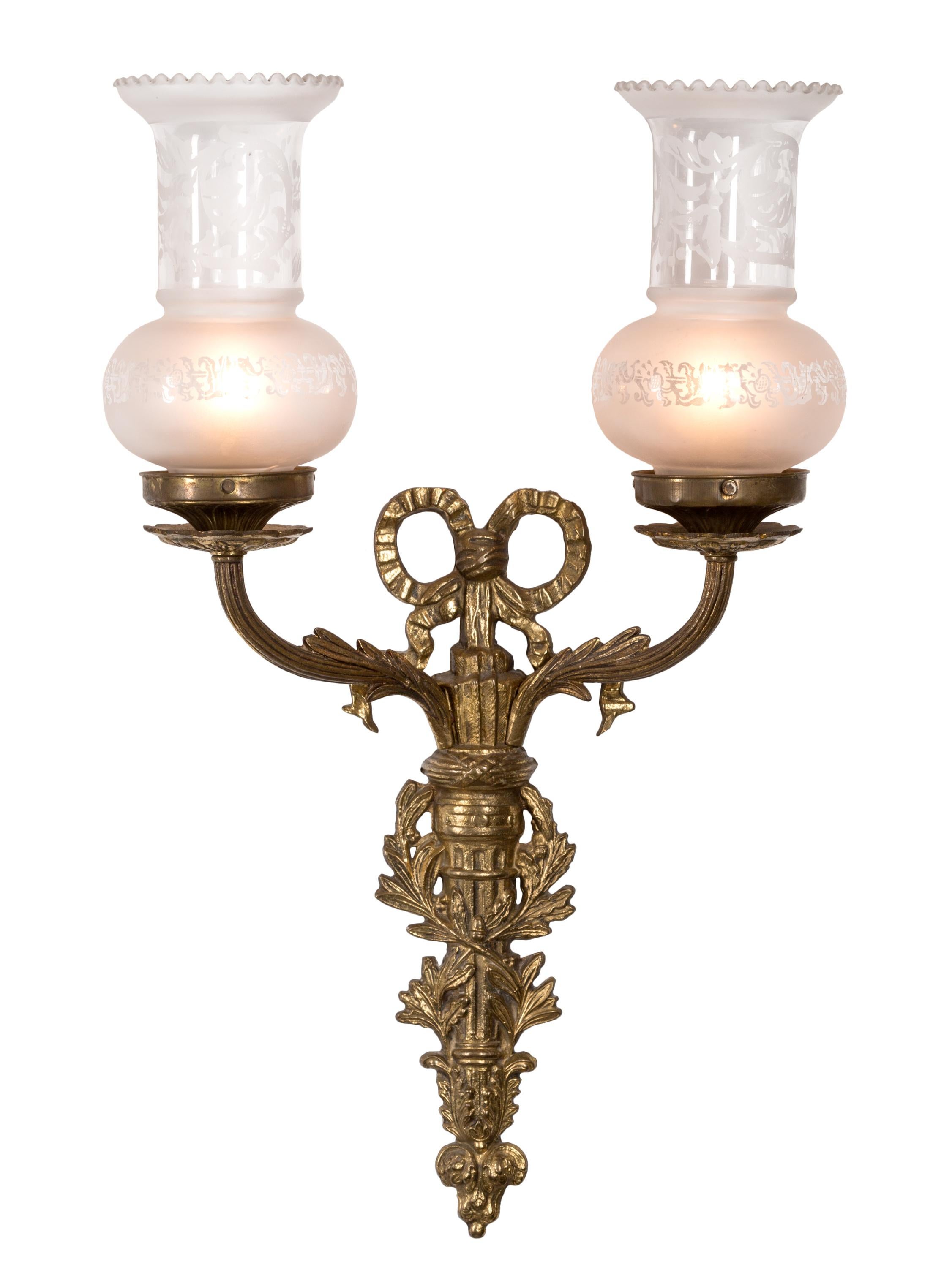 These 19th century French bronze wall sconces or appliqués display a variety of the neoclassical elements found in the Louis XVI style. The central vertical of the sconces seems to mix the forms of both a torch and archer's quiver, the 