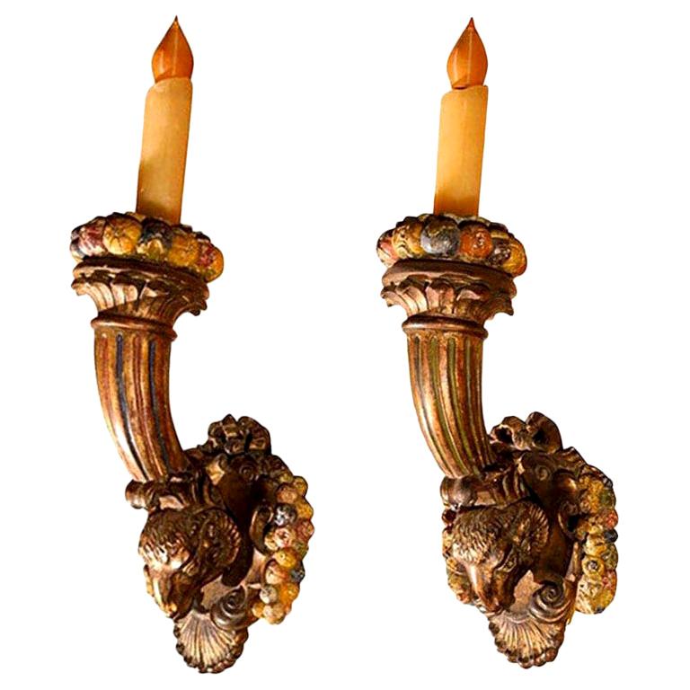 Grand scale and well carved antique French Napoleon III giltwood and polychrome torch sconces with rams heads, and fruit accents. These antique French Louis XVI style or neoclassical style carved wood sconces have a gorgeous warm aged patina and are