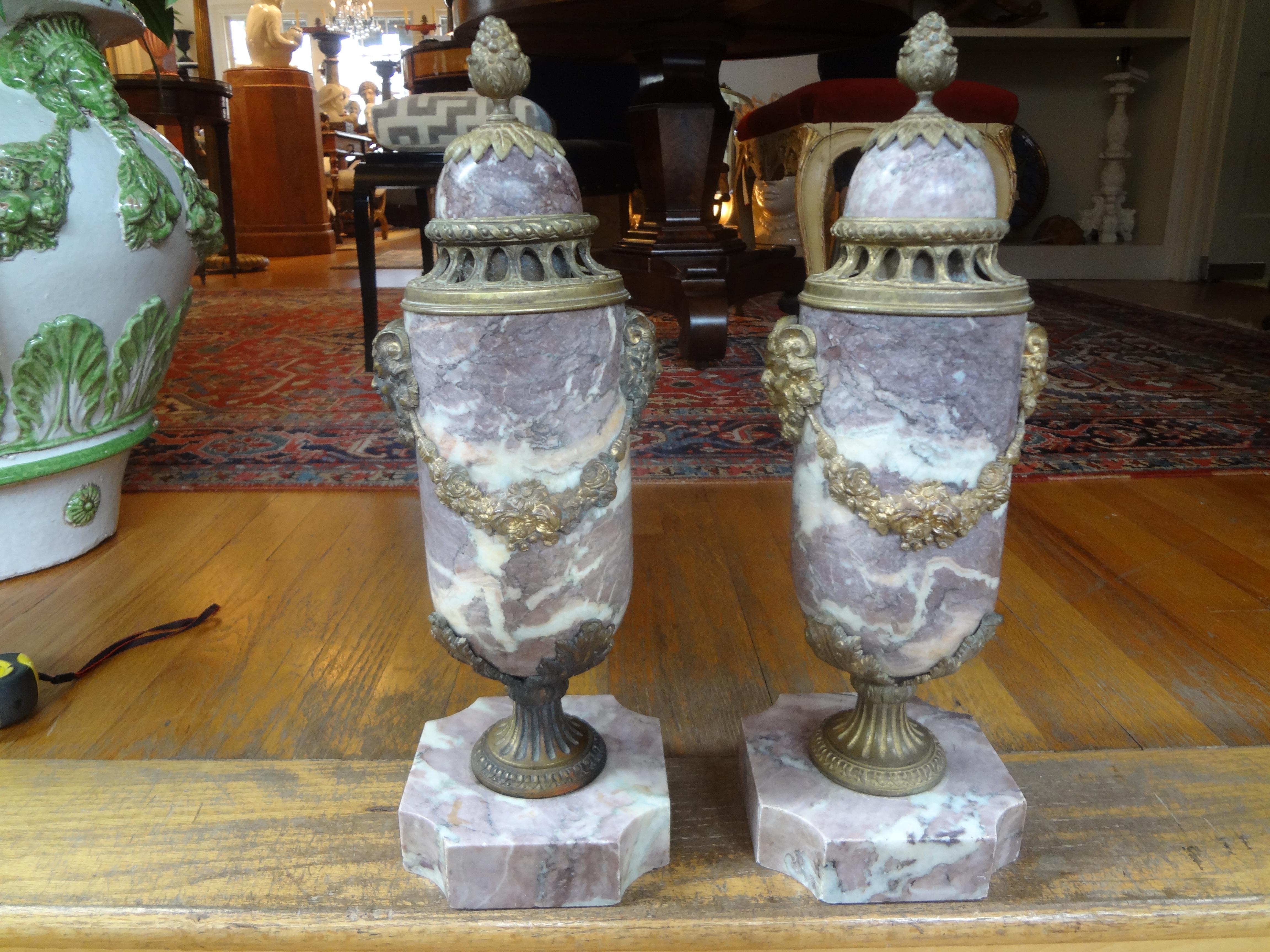 Beautiful pair of 19th century French Louis XVI style or neoclassical style marble urns or cassolettes with gilt metal or bronze accents. These antique French Napoleon III marble urns or garniture are a versatile pair that could be used in many