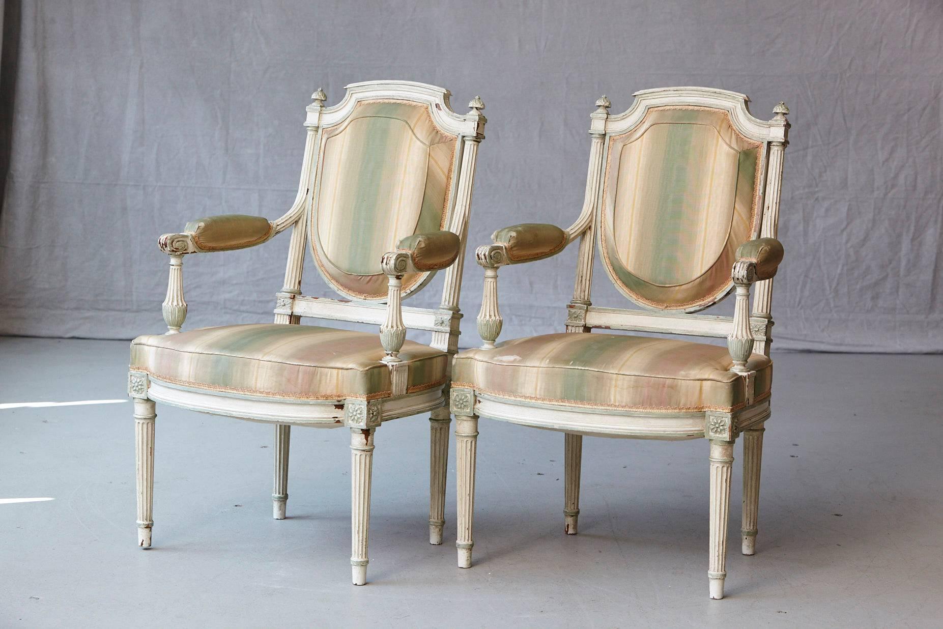 Exceptional pair of 19th century French Louis XVI style painted fauteuils.
The chairs have Greek inspired geometrical fluted legs which continue in the upper back part of the frames and divert into the arms. Shield shaped seat backs.
The chairs