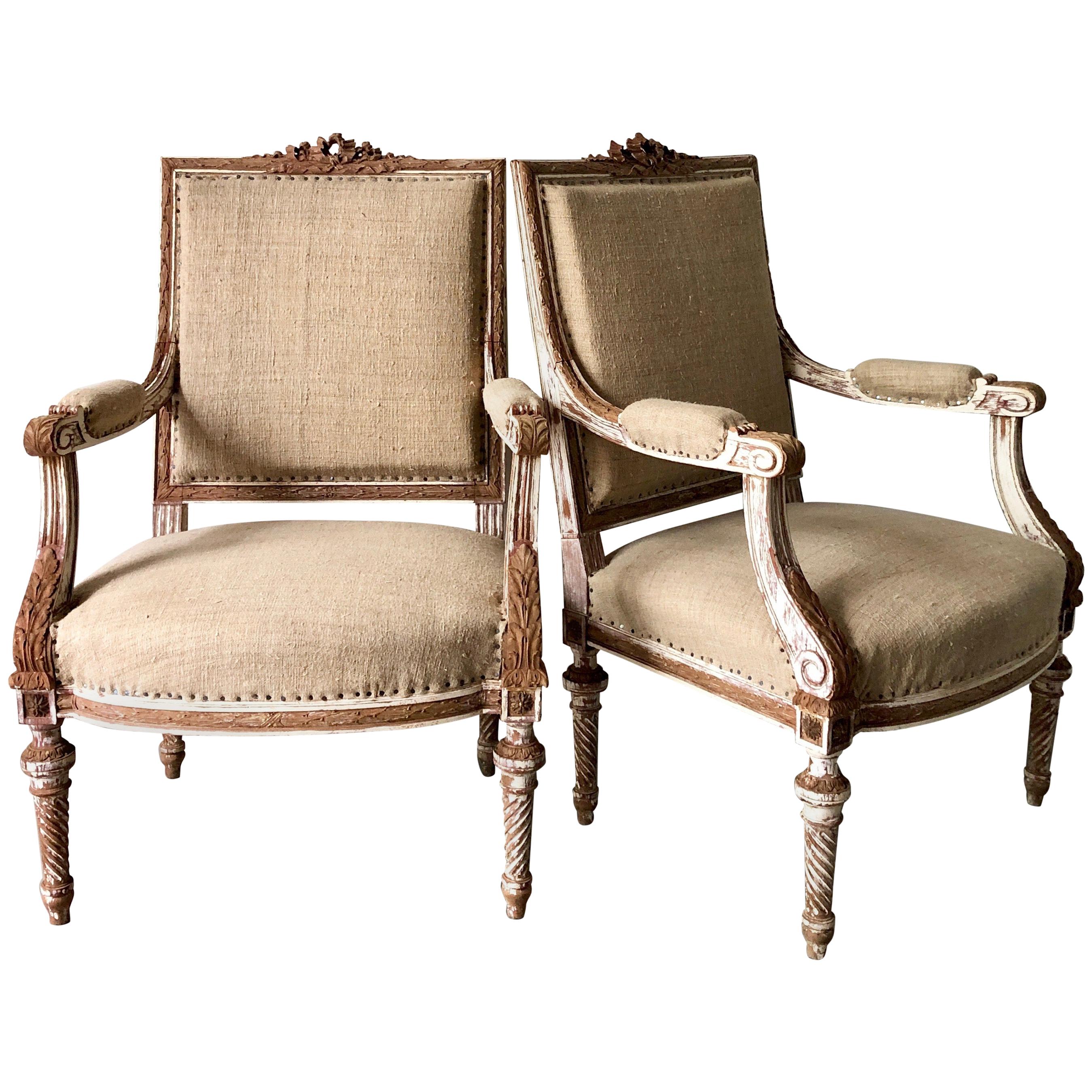 A pair of 19th century French armchairs à la reine with flat back and richly carved solid wood frame with ribbons, acanthus and rosettes on conical twisted fluted legs, showing some places fragments of original giltwood.
Upholstered in raw