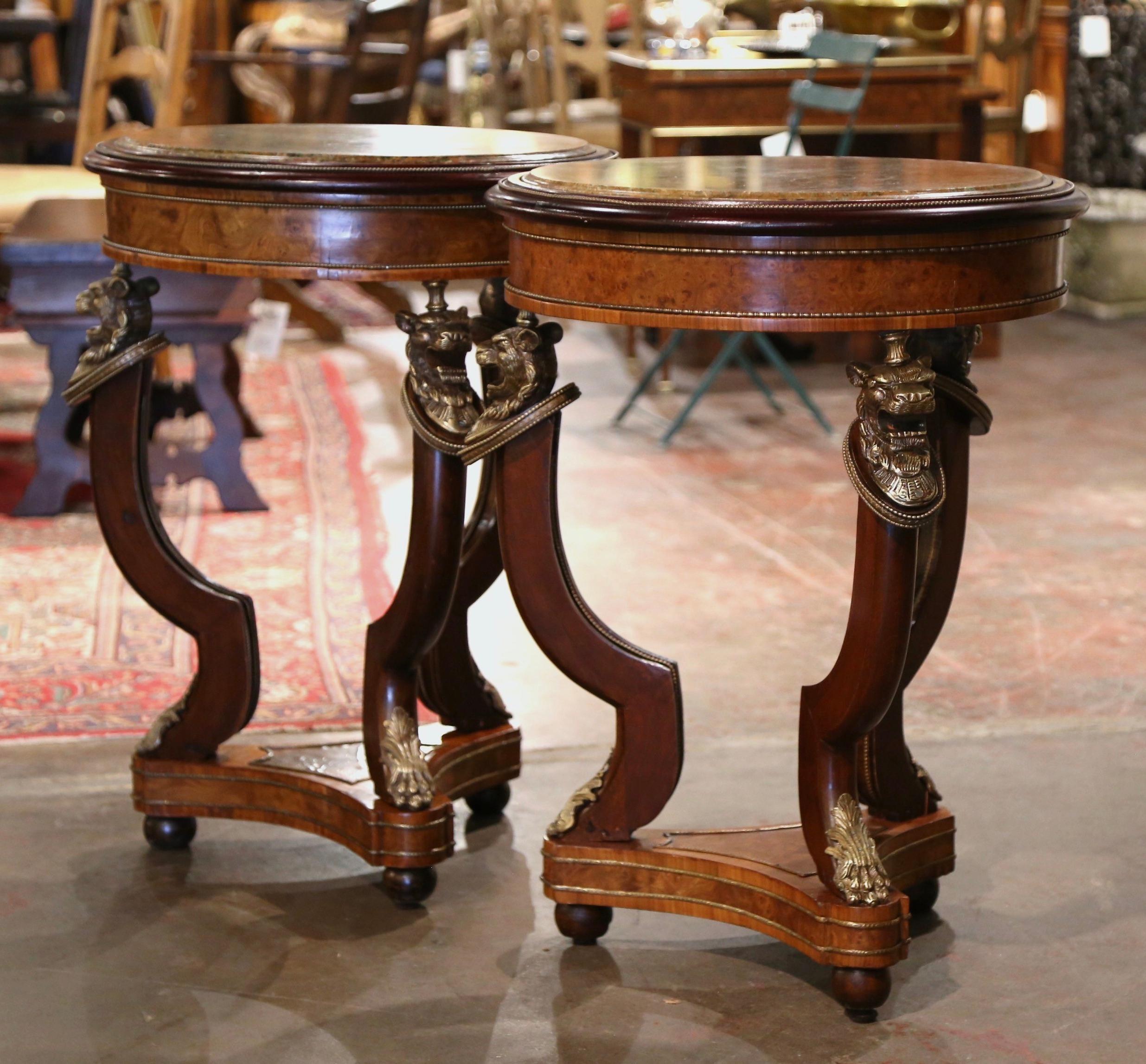 Decorate a living room or den with this elegant pair of antique round gueridons. Crafted in France circa 1870, each fruit wood table stands on three cabriole legs decorated with bronze lion head figures mounts at the shoulders, and ending with