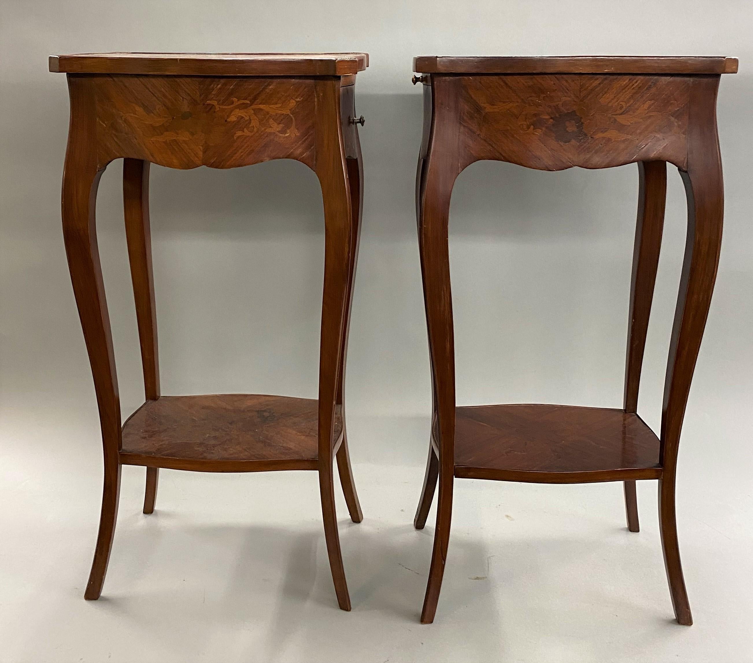 A fine pair of French rosewood end tables with foliate marquetry, each with a shaped top and single conforming drawer, as well as a candle slide on the back with gilt bordered tooled leather, supported by slender cabriole legs and a marquetry single