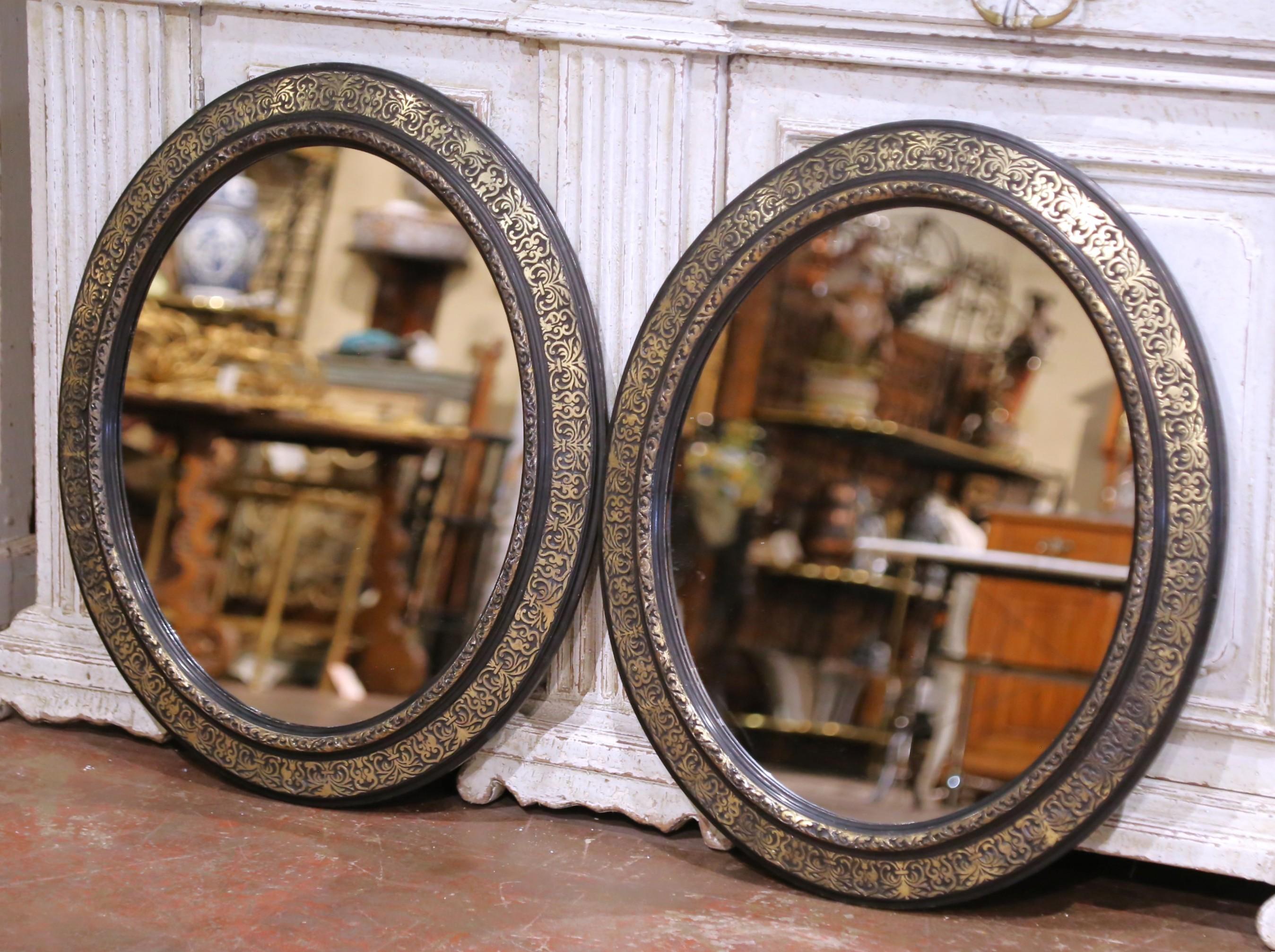 Cette paire de miroirs ovales français anciens rehausse tout espace. Fabriqué en France vers 1880 pendant la période Napoléon III, chaque miroir présente un cadre moulé fini en noir profond et décoré de motifs complexes de feuillages et de palmettes