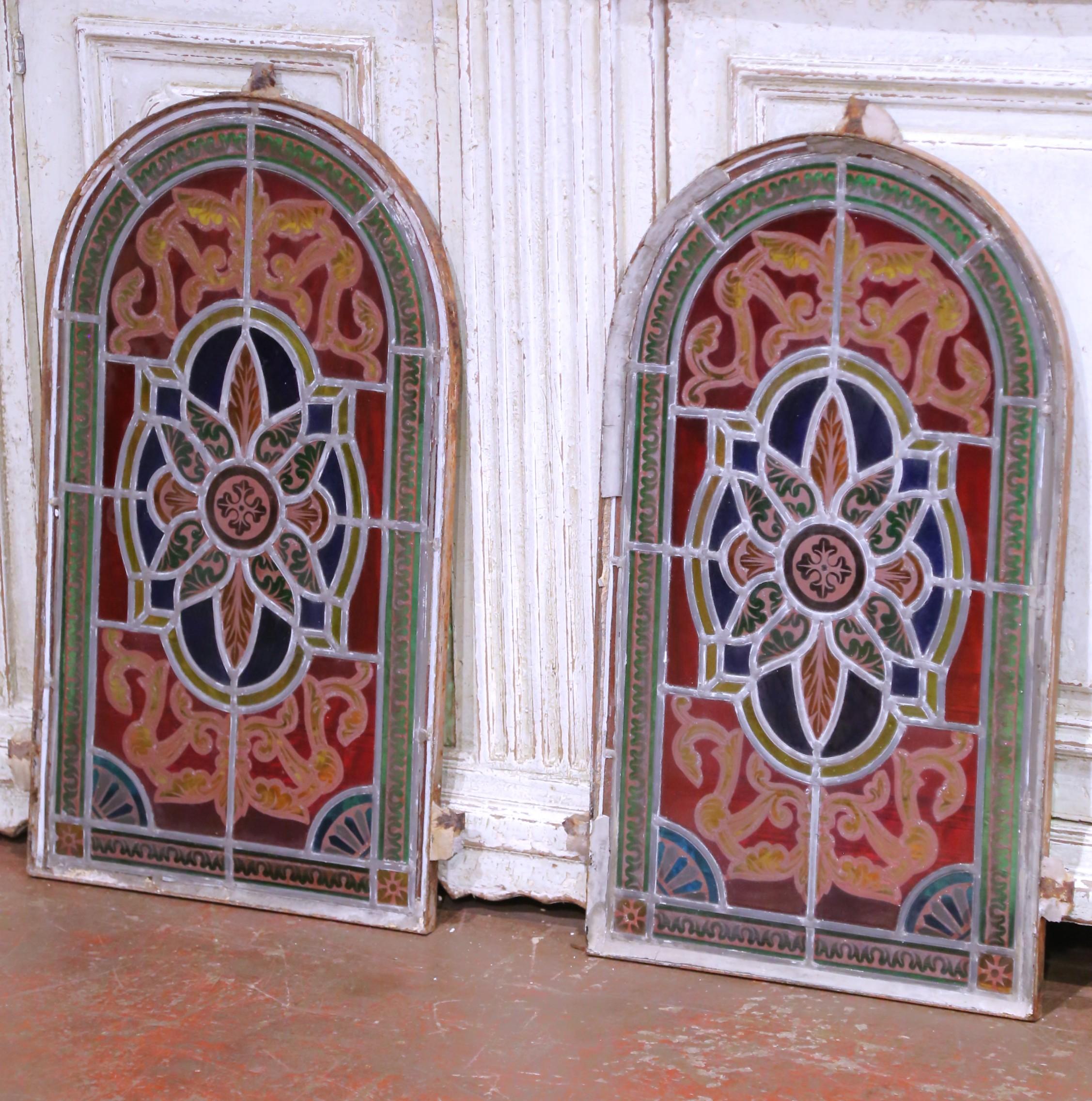 Realizzata in Francia intorno al 1850, questa squisita coppia di vetrate antiche ad arco è un esempio di arte della metà del XIX secolo, risalente al periodo di Napoleone III. Ogni pannello presenta una composizione ricca di colori con un medaglione
