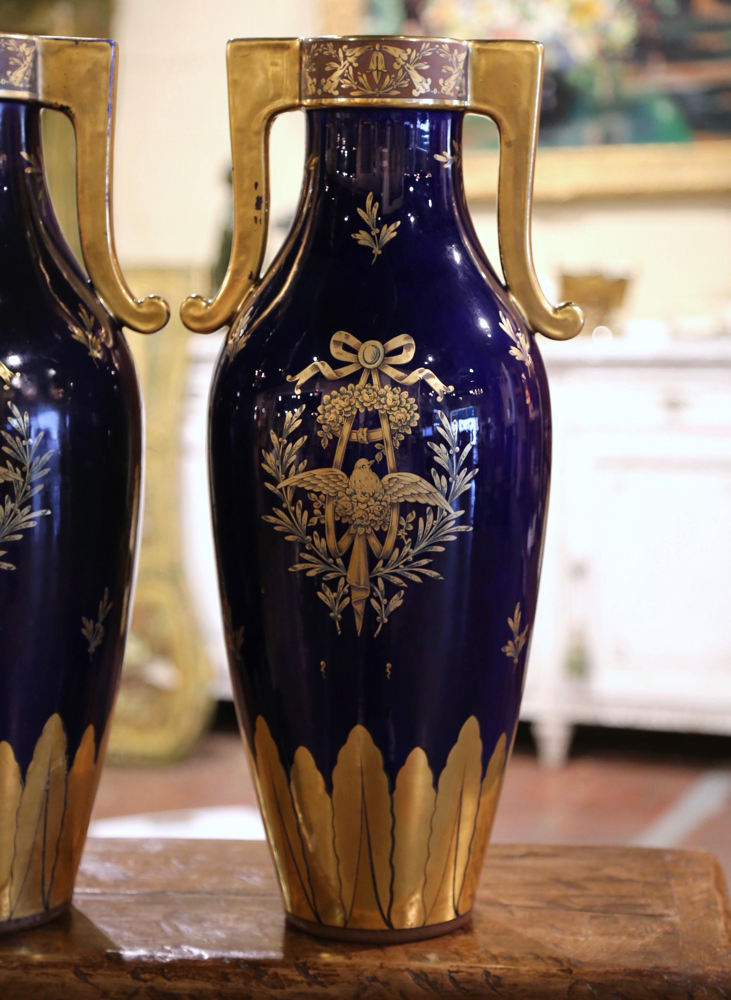 Decorate a console or a buffet with this elegant pair of antique urns from Paris. Crafted circa 1890 and signed on the bottom, each tall neoclassical vase features a long neck with side handles. The 