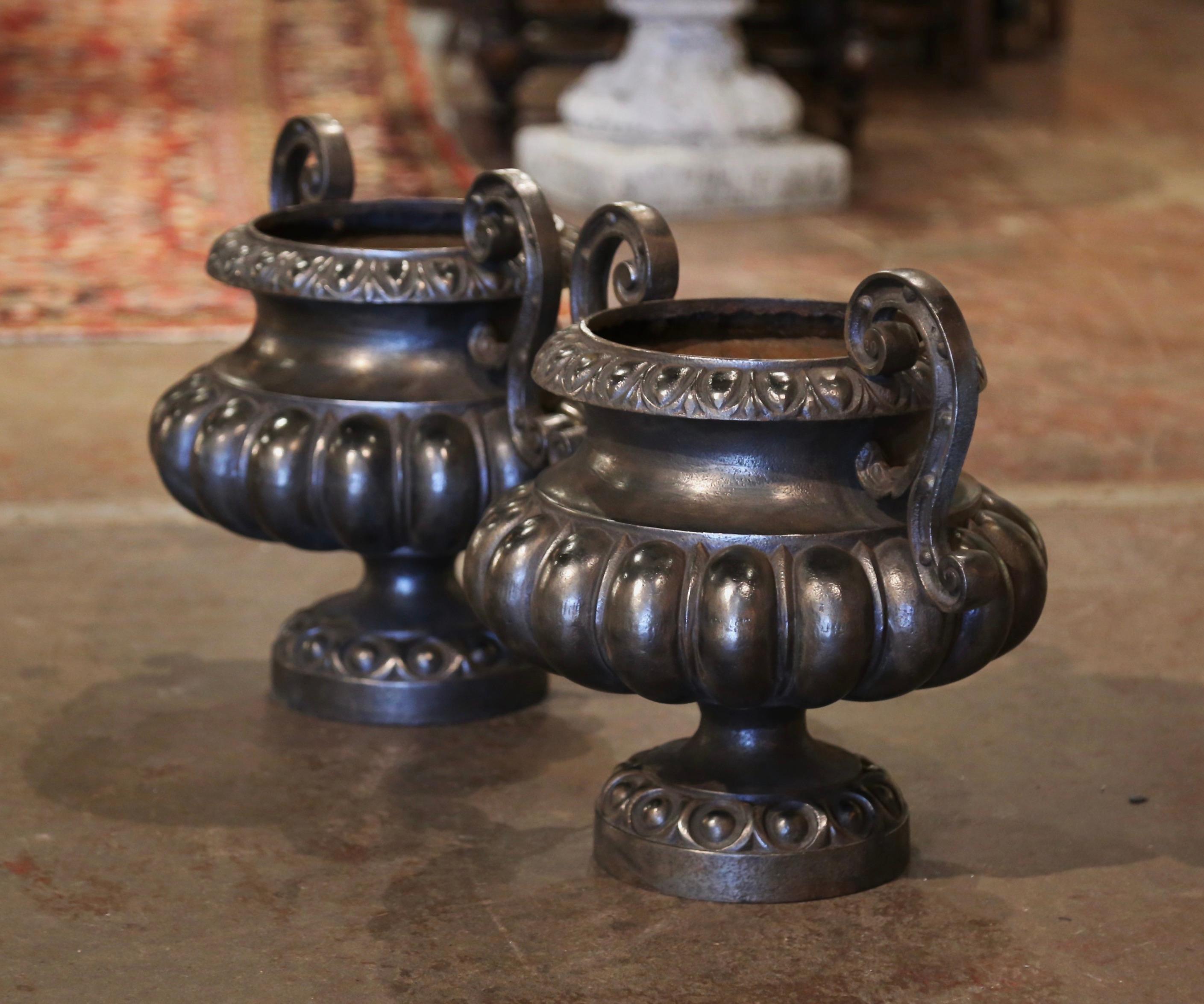Crafted in France circa 1880 in the neoclassical style, the antique planters have a stately, elegant style. Each round vase stands on a circular base over foot, and features a flared rim with egg-dart molding, and dual scrolled foliate handles over