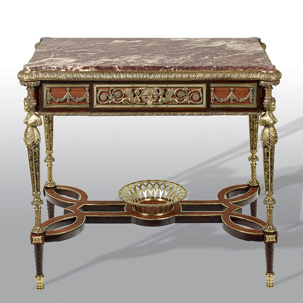An extremely fine pair of French gilt bronze mounted mahogany table de milieu, in the manner of Adam Weisweiler. The rectangular inset fleur de pecher marble tops above a panelled frieze applied with a pierced scrolling vine mount, with one long