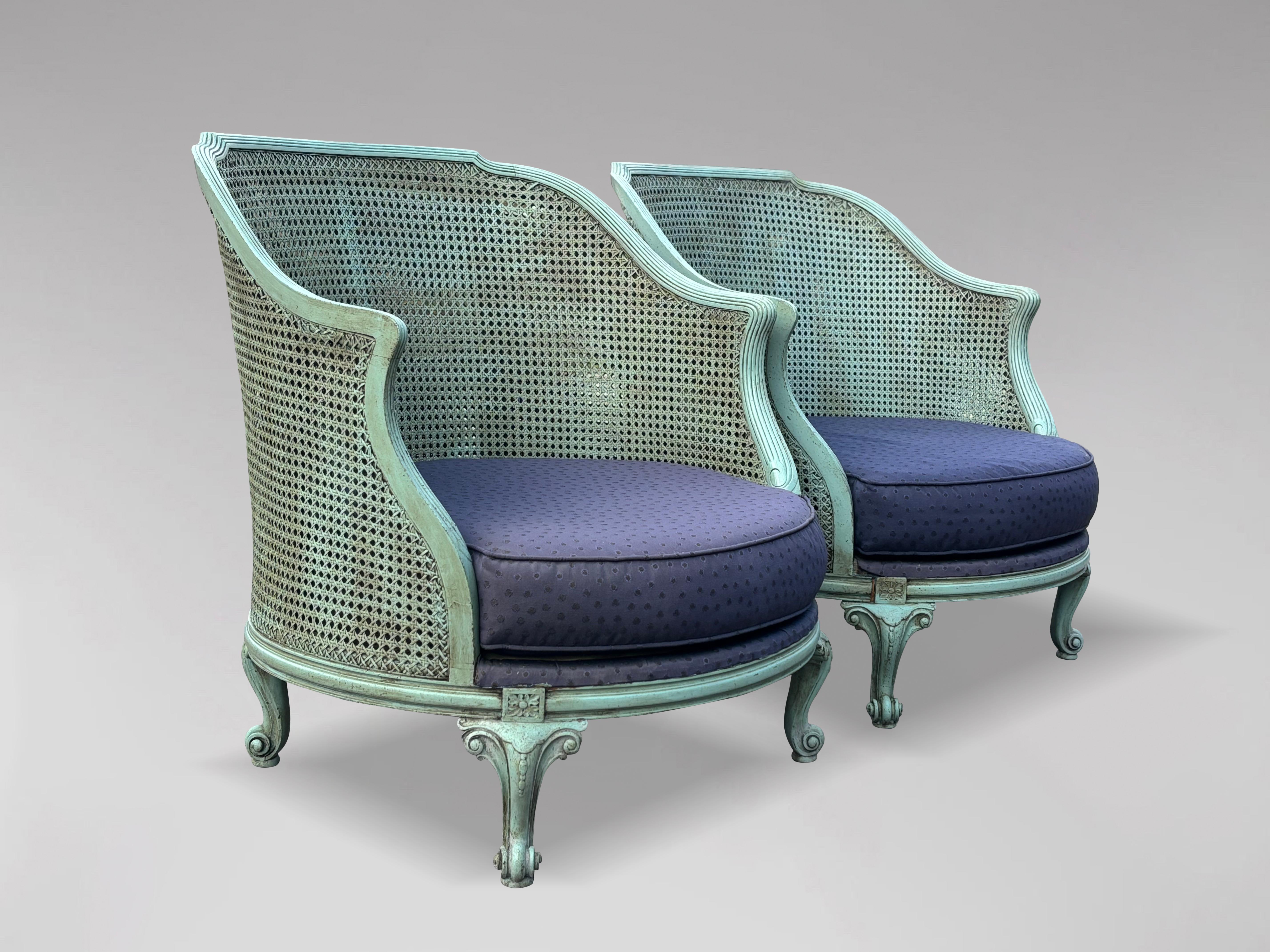 An amazing pair of French 19th century Louis XV style painted bergère armchairs. The armchairs feature a large gracefully curved frame inset with double caned back and sides. Comfortable open form, the wide demi-lune back rest with short arms.