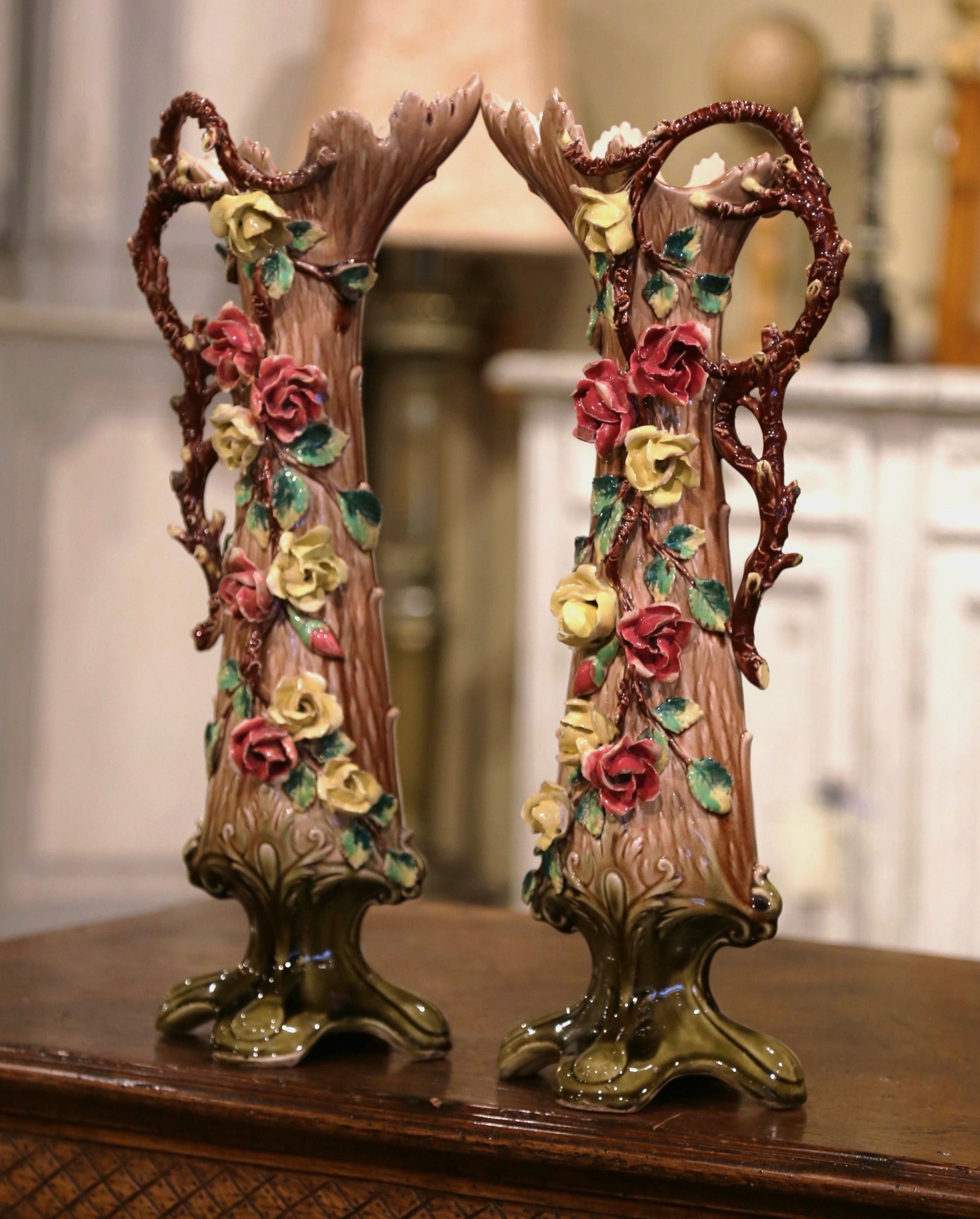 Beautifully sculpted and colorful, this pair of antique Majolica vases would be a wonderful addition to a mantel, tabletop or bookshelf. Crafted in France, circa 1870, each hand painted piece stands on four curved feet and features a wide and