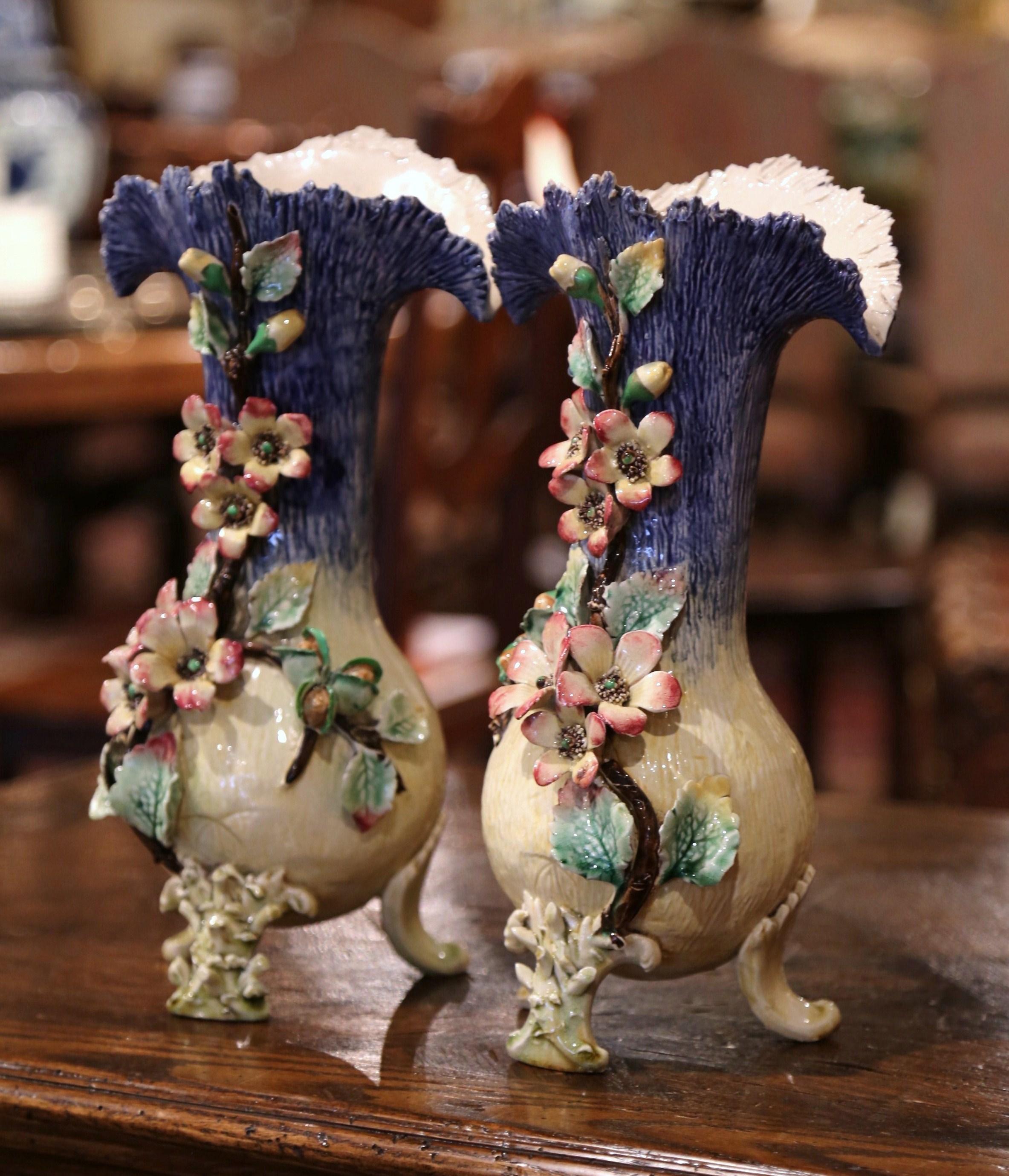 Beautifully sculpted and colorful, this pair of antique Majolica vases would be a wonderful addition to a mantel, tabletop or bookshelf. Crafted in France, circa 1870, each hand painted piece stands on three curved feet and features a wide and