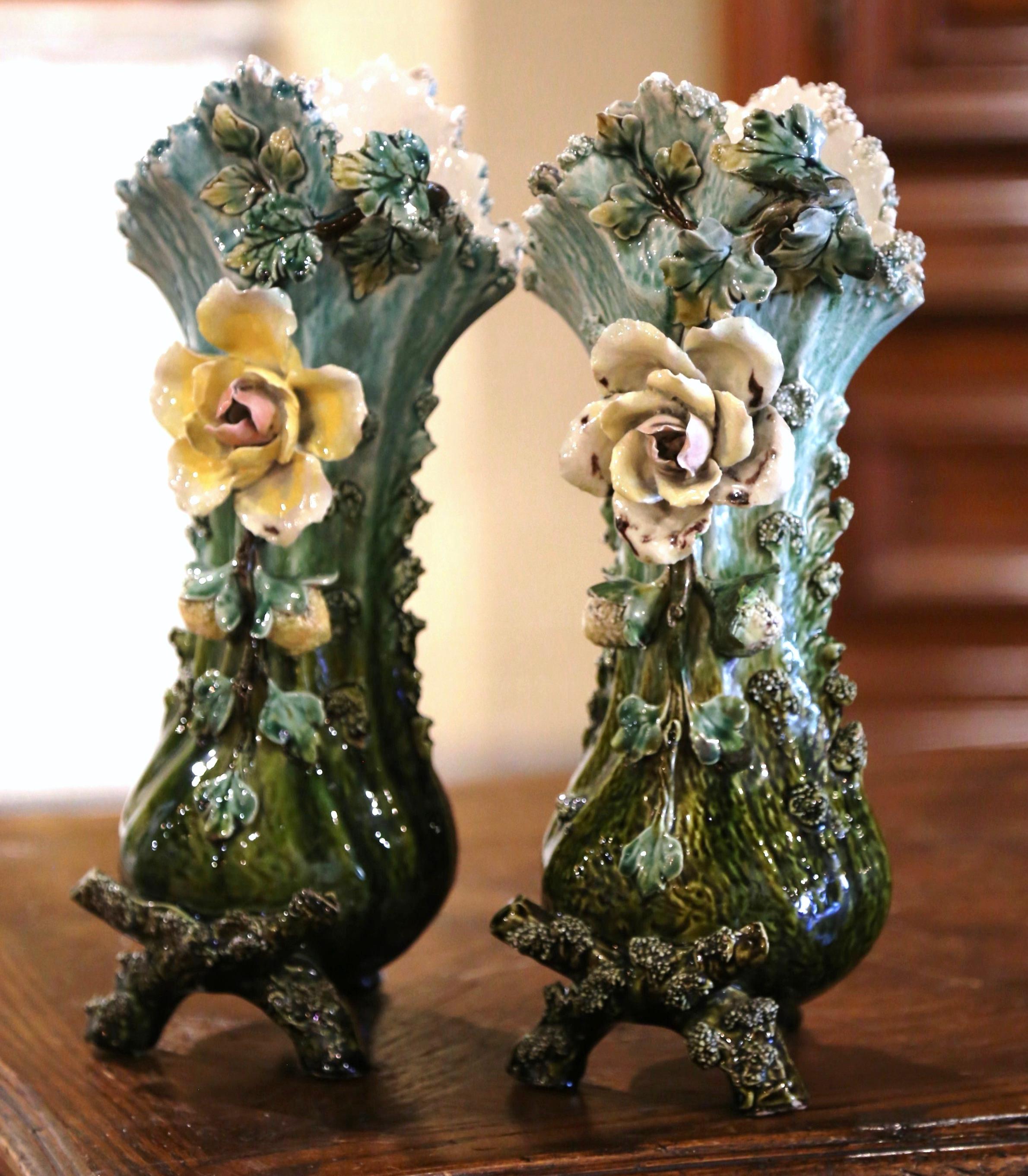 Beautifully sculpted, this pair of antique majolica vases would be a wonderful addition to a mantel, tabletop or bookshelf. Crafted in France, circa 1880, each hand painted piece stands on three branch form legs over a long neck embellished with a