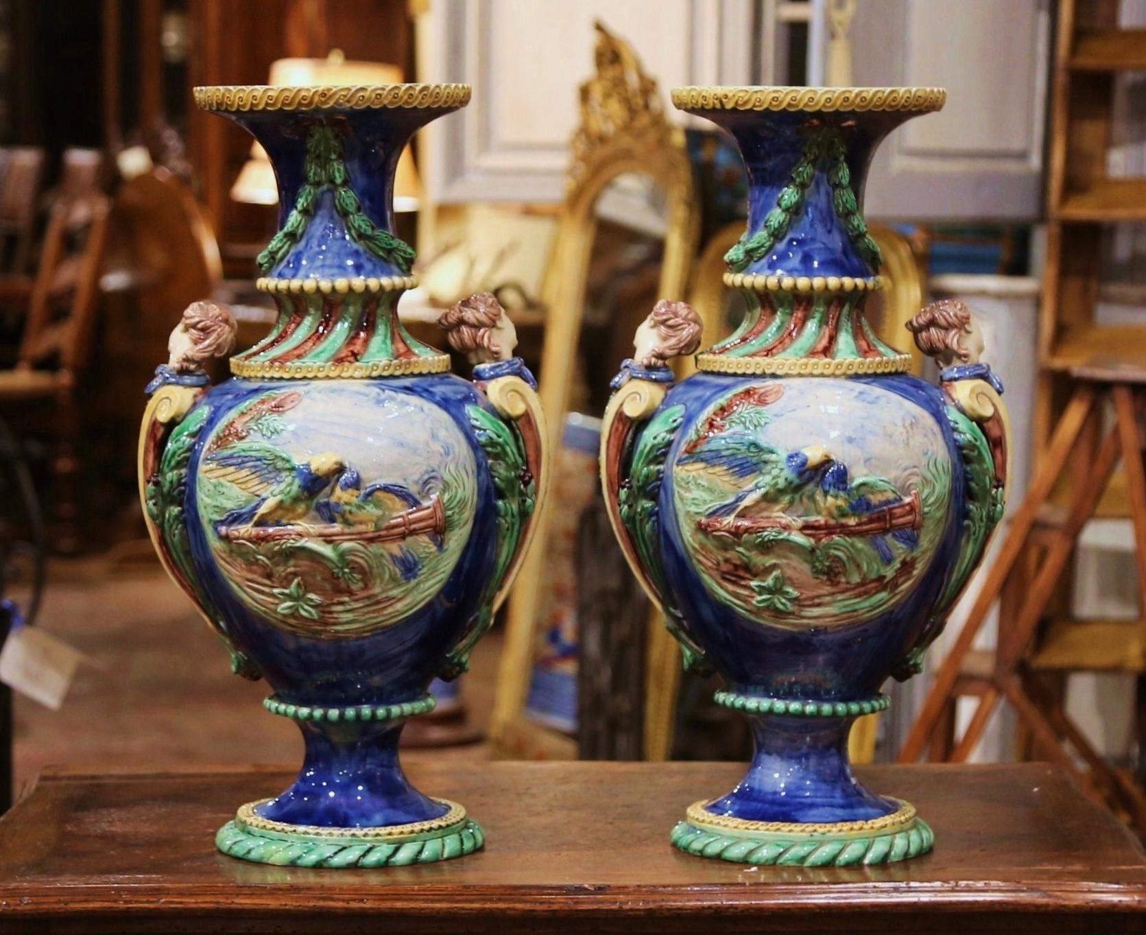 These elegant antique Majolica vases were crafted in France, circa 1870. Attributed to the French artist Thomas Sergent (1830-1890), each tall vessel dressed with carved woman figure handles, stands on a round base and features high relief