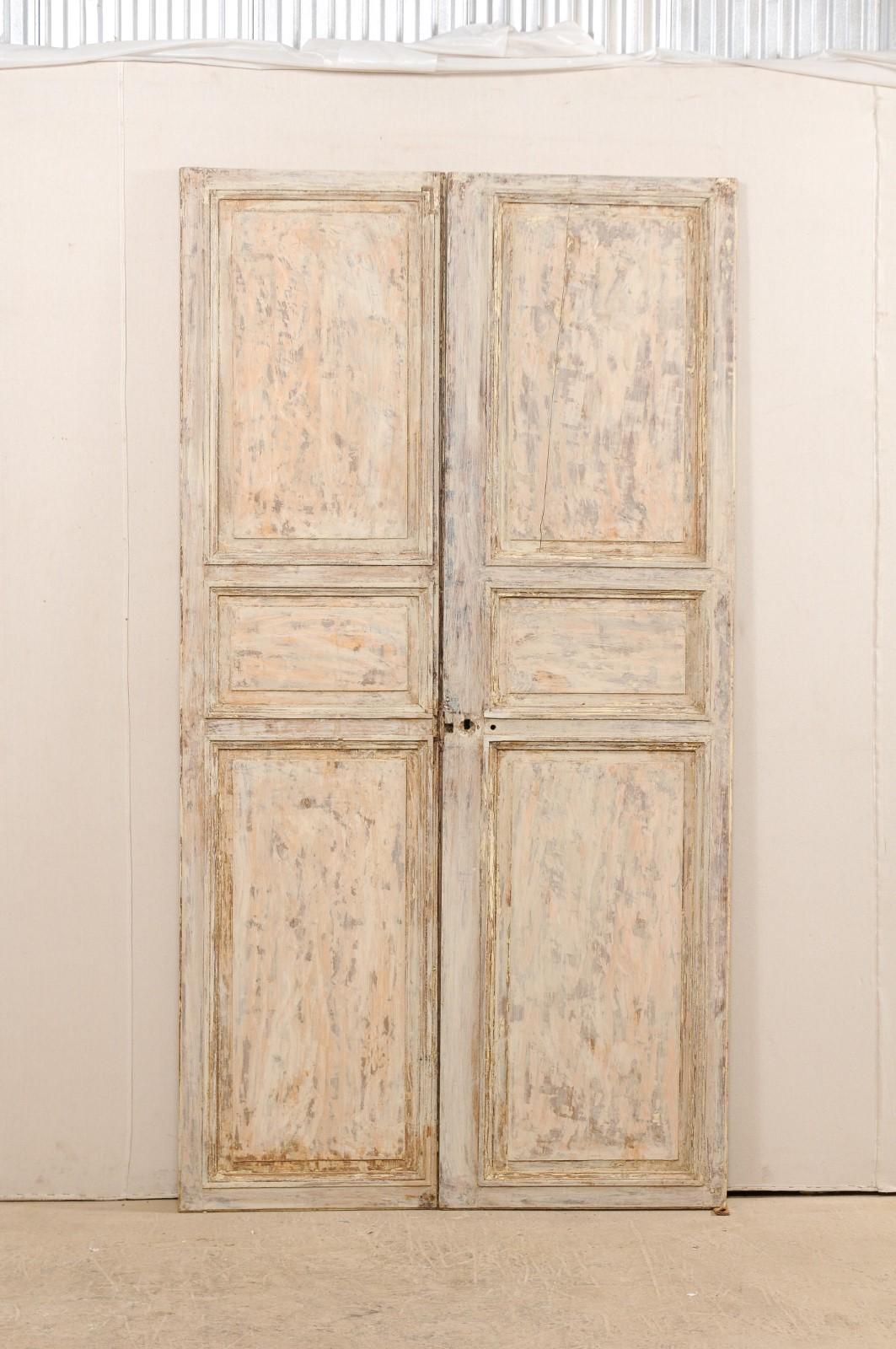 A pair of French doors from the 19th century. This pair of French doors, just over 8 feet in height, each have three recessed panels at front and backsides, with smaller center panel flanked between longer ones at the top and bottom sections of the
