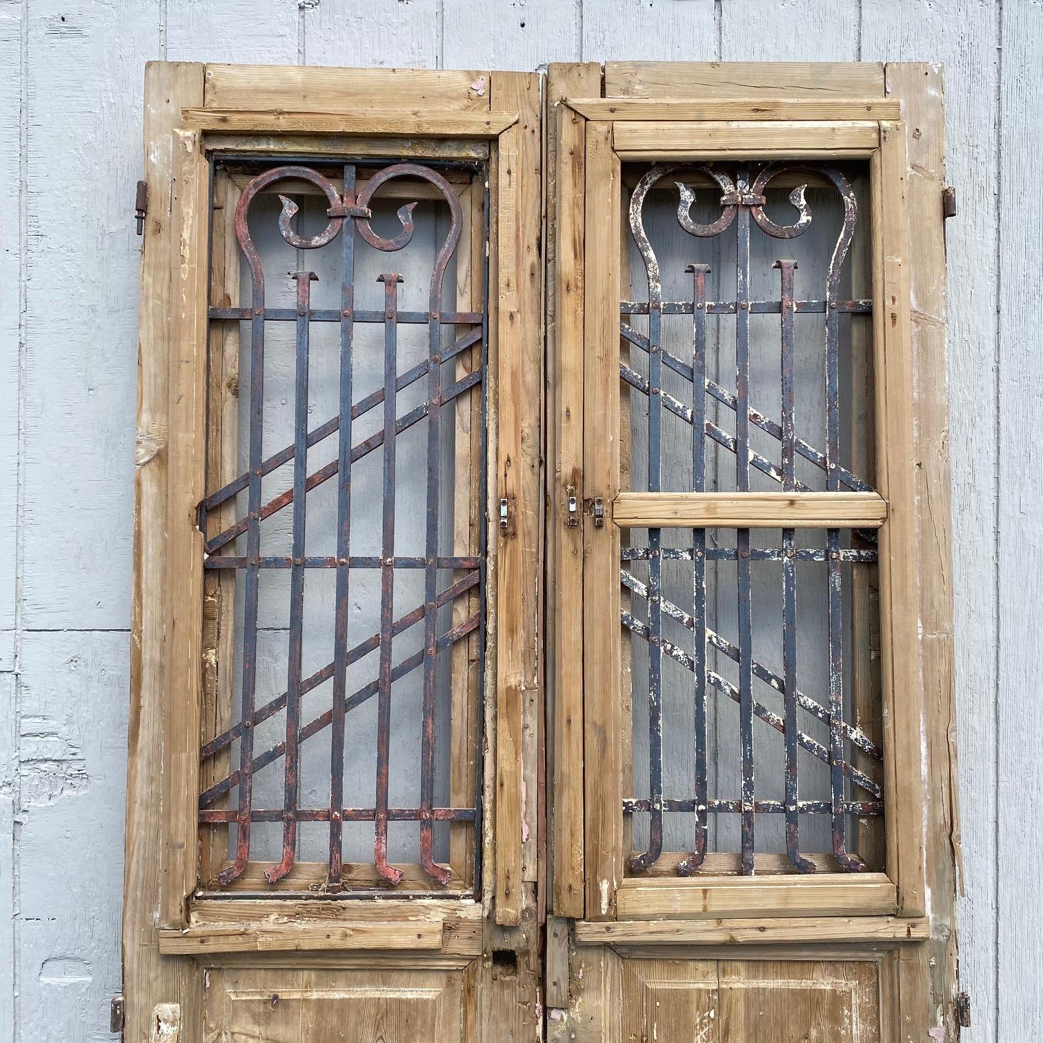 Pair of stunning stripped 19th century French doors with wrought iron, featuring bold molded detail framing the lower panels as well as the intricate wrought iron inserts above, which are artfully wrought in a beautiful geometric pattern. These