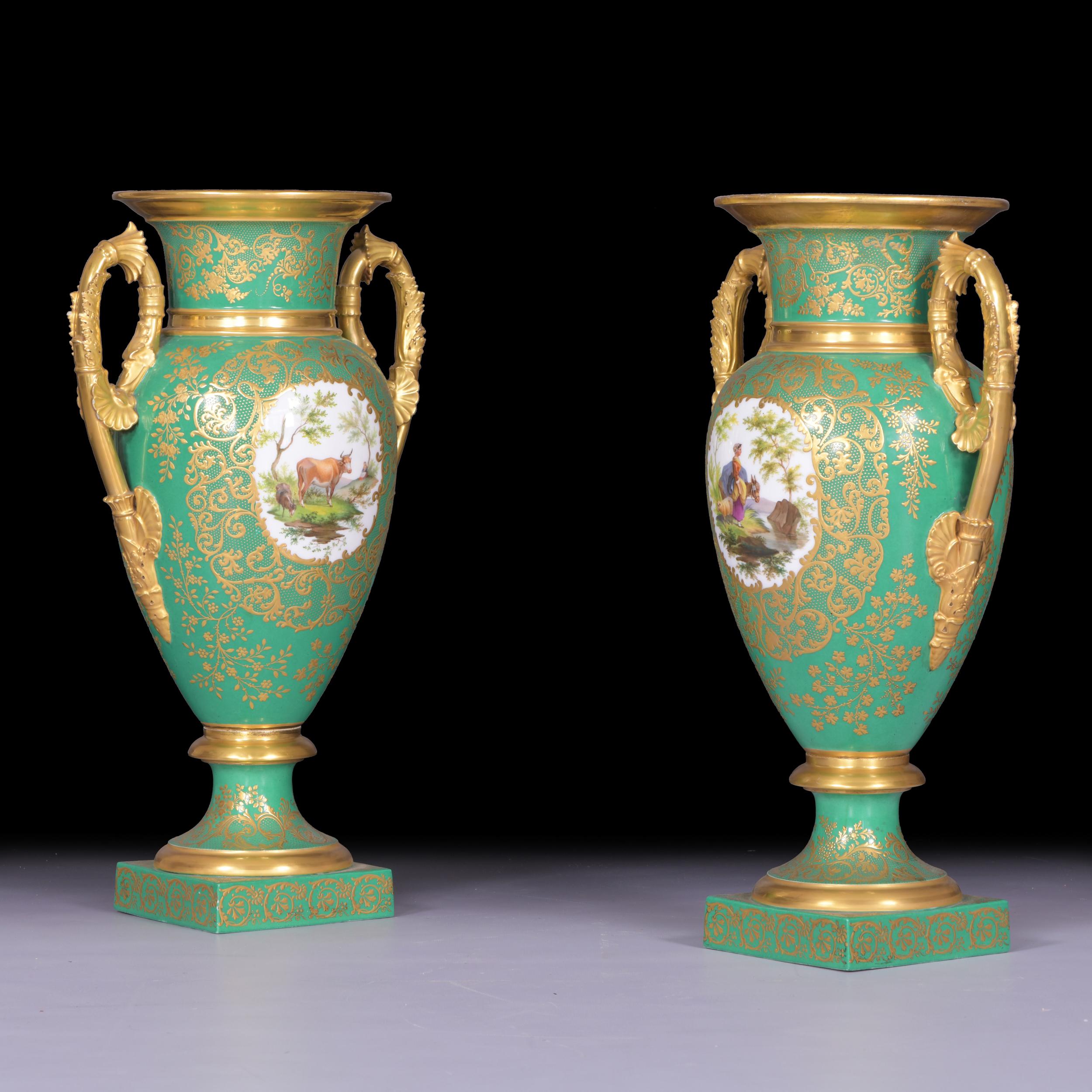 A fine pair of antique porcelain vases, dating from the early 19th century in the Empire period, set on a square base and spreading socle, the front of the body of the vase is painted with a idealised scene. The idyllic pastoral scene shows a noble