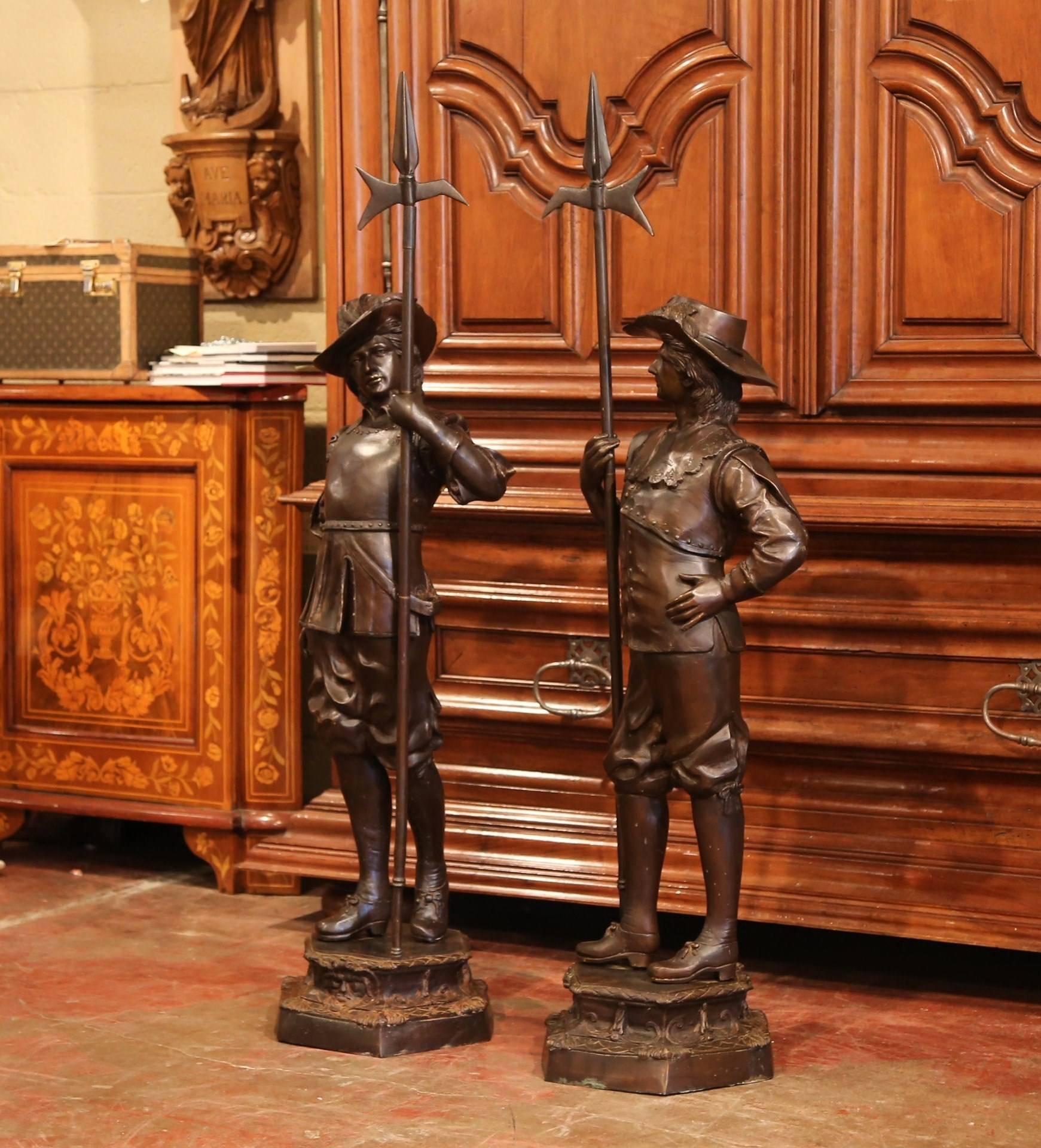 Place this large pair of antique sculptures on either side of your front door to guard your entry! Crafted in Southern France, circa 1880, the spelter patinated figures depict two French musketeers in traditional clothing holding a spear. Each