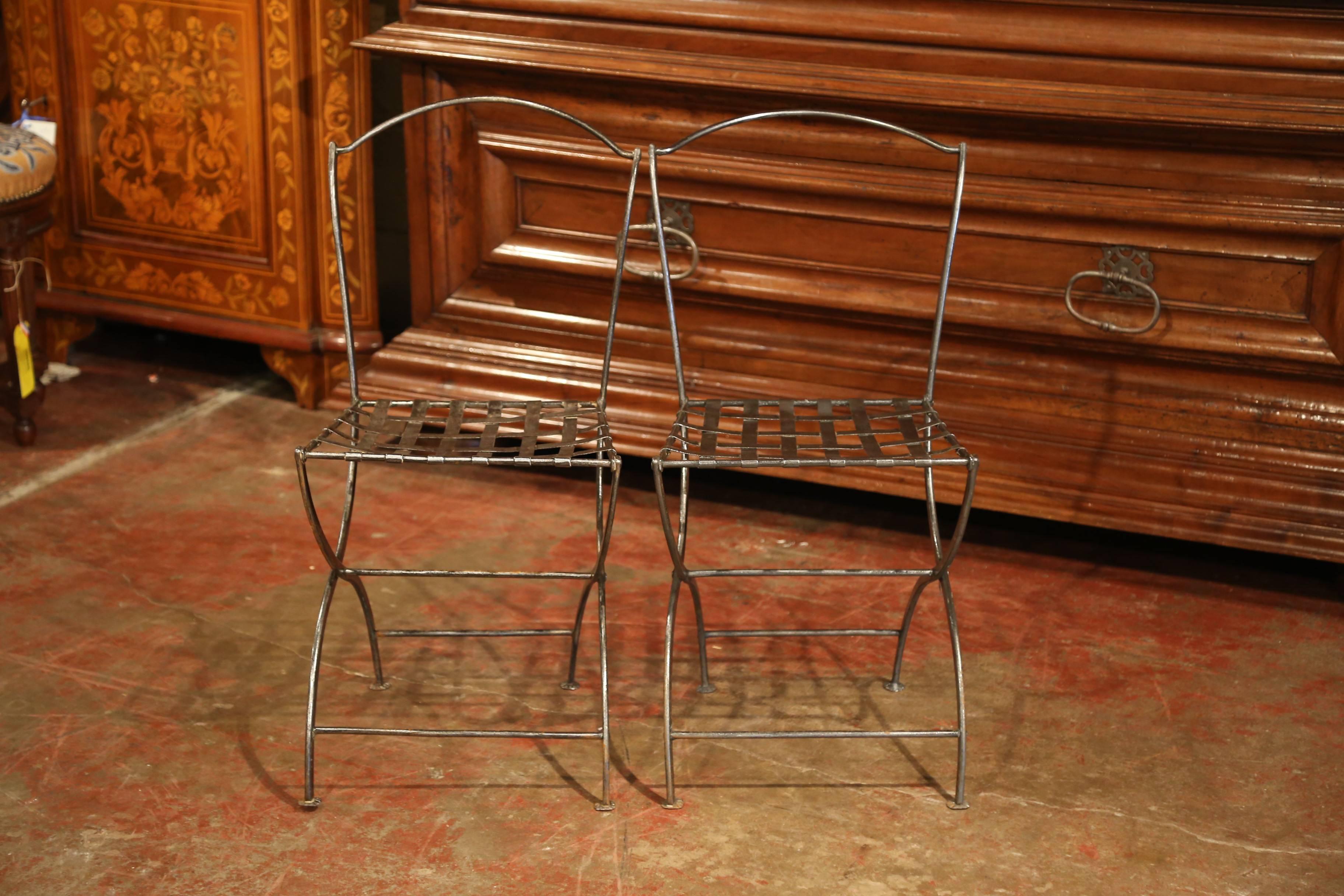 Place this pair of antique side chairs around a bistrot table on a covered patio. Forged in France circa 1880, the iron chairs have an arched back, curved legs and a woven metal seat. The simple, slim chairs are in excellent condition, a rich