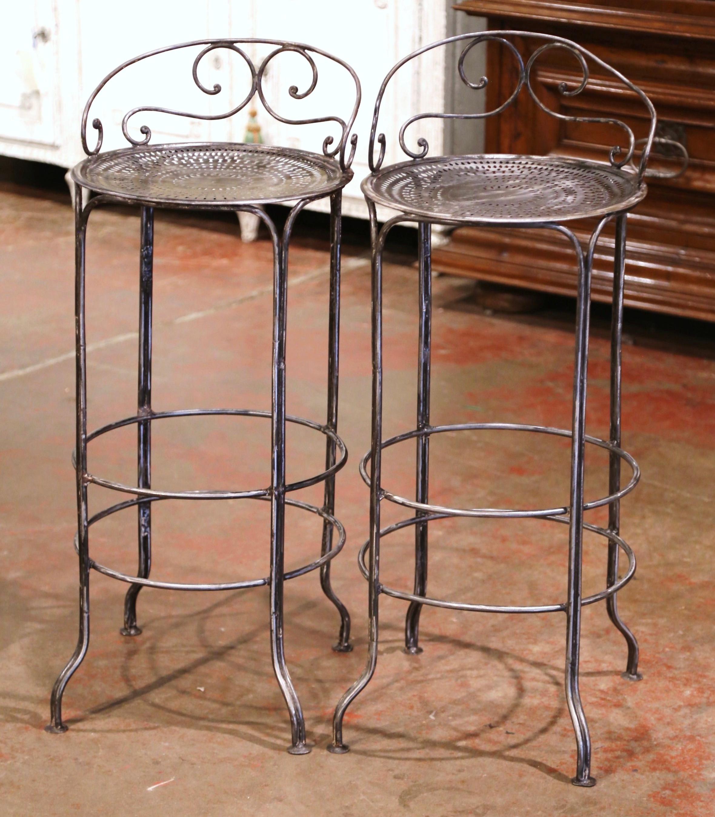 Place these two antique barstools around a bar, or outside around a pool counter! Crafted in France circa 1880 and made of forged iron, each sturdy chair stands on straight legs with curved feet, embellished with a circular double bottom footrest