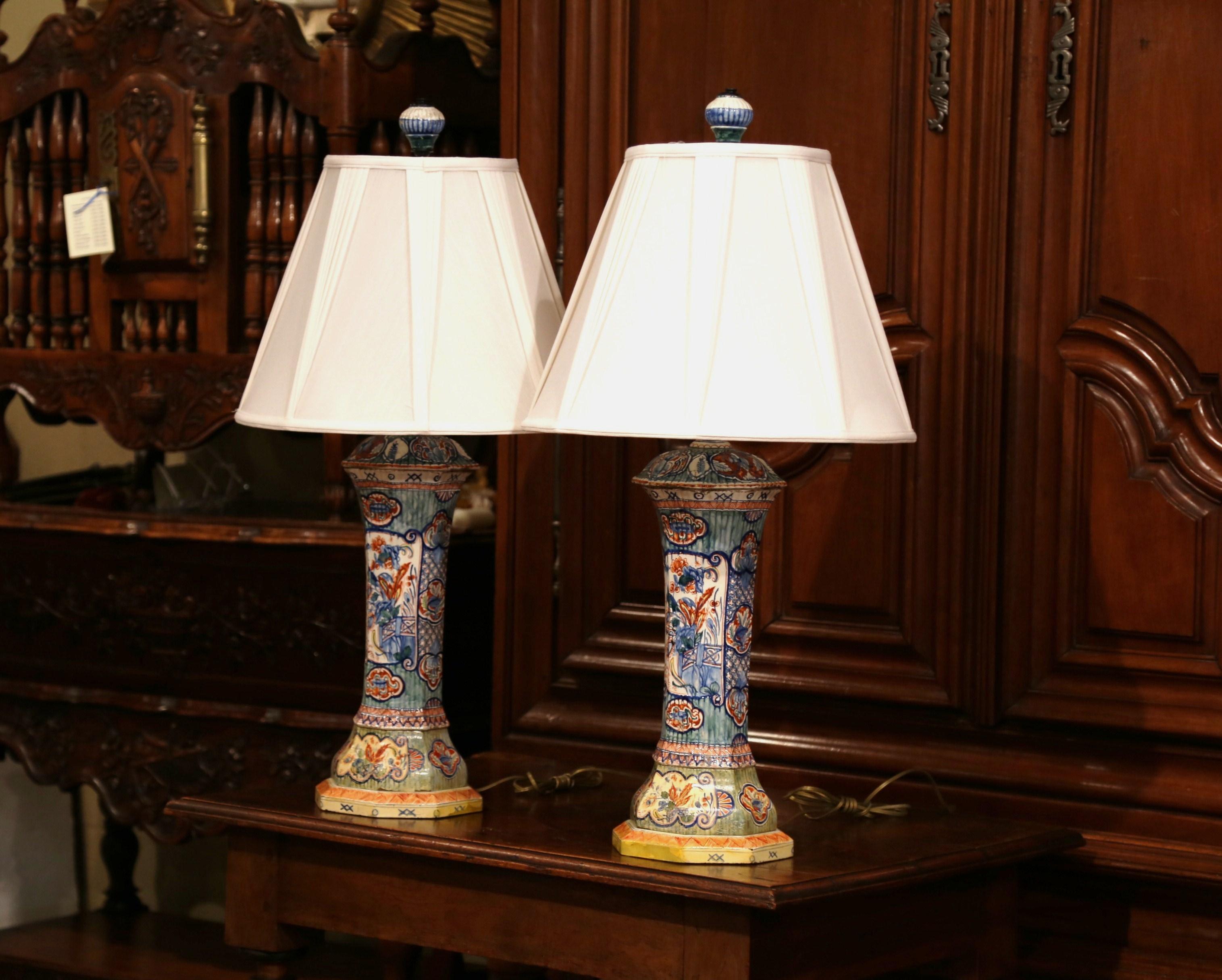 Decorate your bedside tables or living room side tables with these large, colorful antique lamps. Made in France circa 1890, each porcelain base stands on a painted wooden base and is hand painted with Asian-inspired bird and floral decor. Both