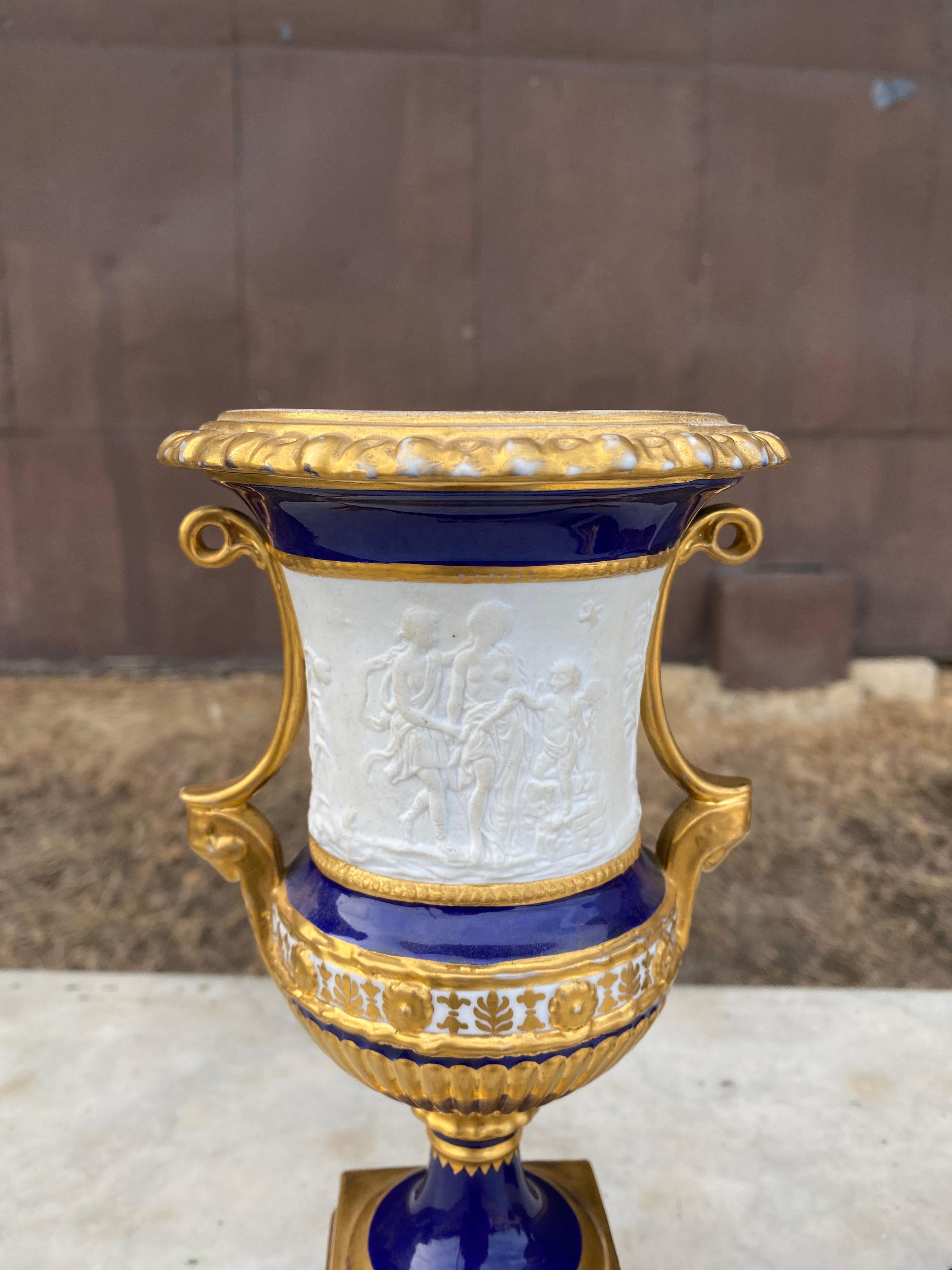 Attractive pair of 19th century French porcelain urns with 
Neoclassical scenes. The urns are parcel gilt decorated.