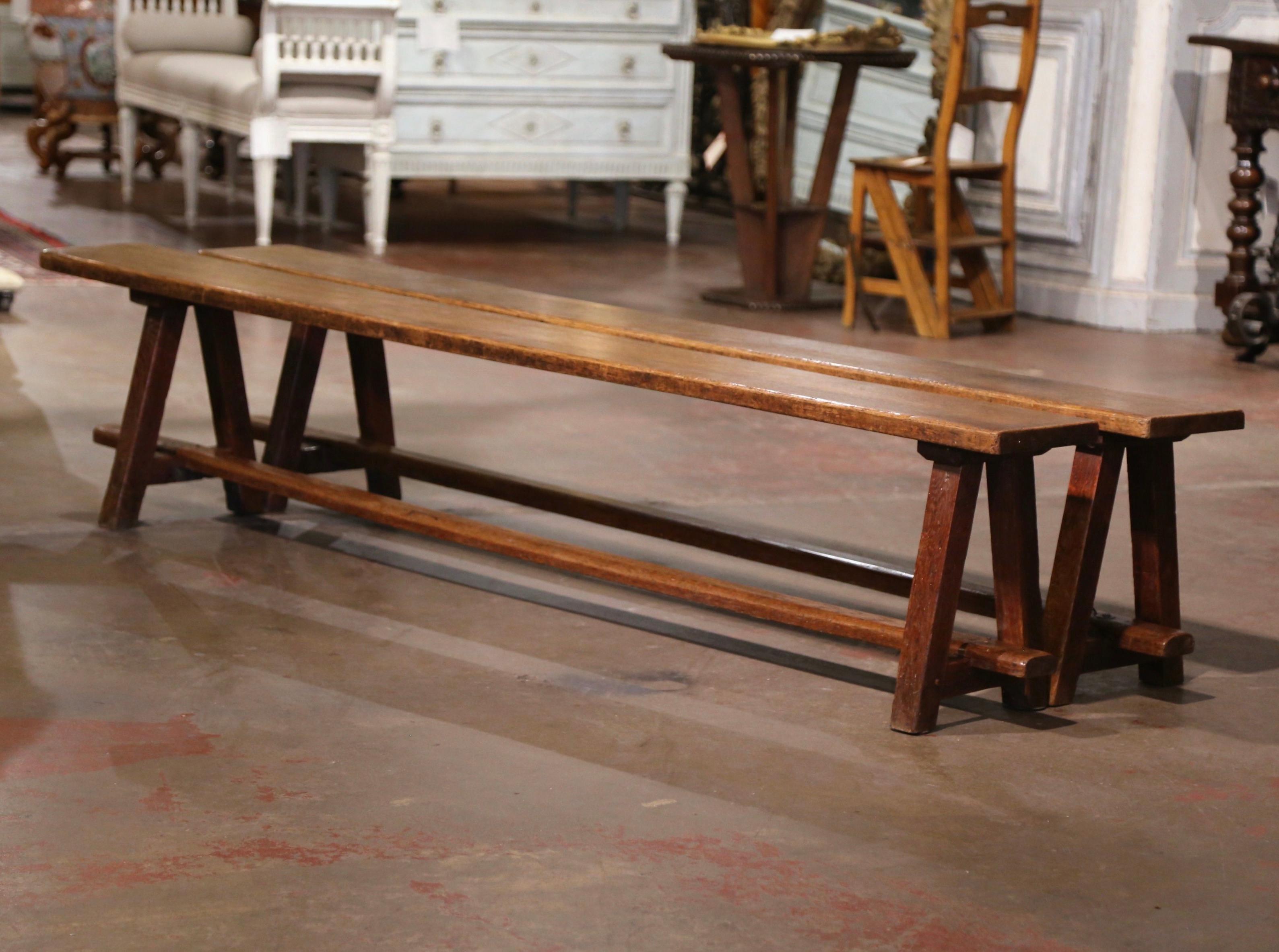 Dress a farm table with these elegant antique provincial benches. Crafted in Normandy, France circa 1880, and carved of oak wood, the sturdy farmhouse benches stands on joined A-fame legs and joined by a central stretcher. Each seat is built with