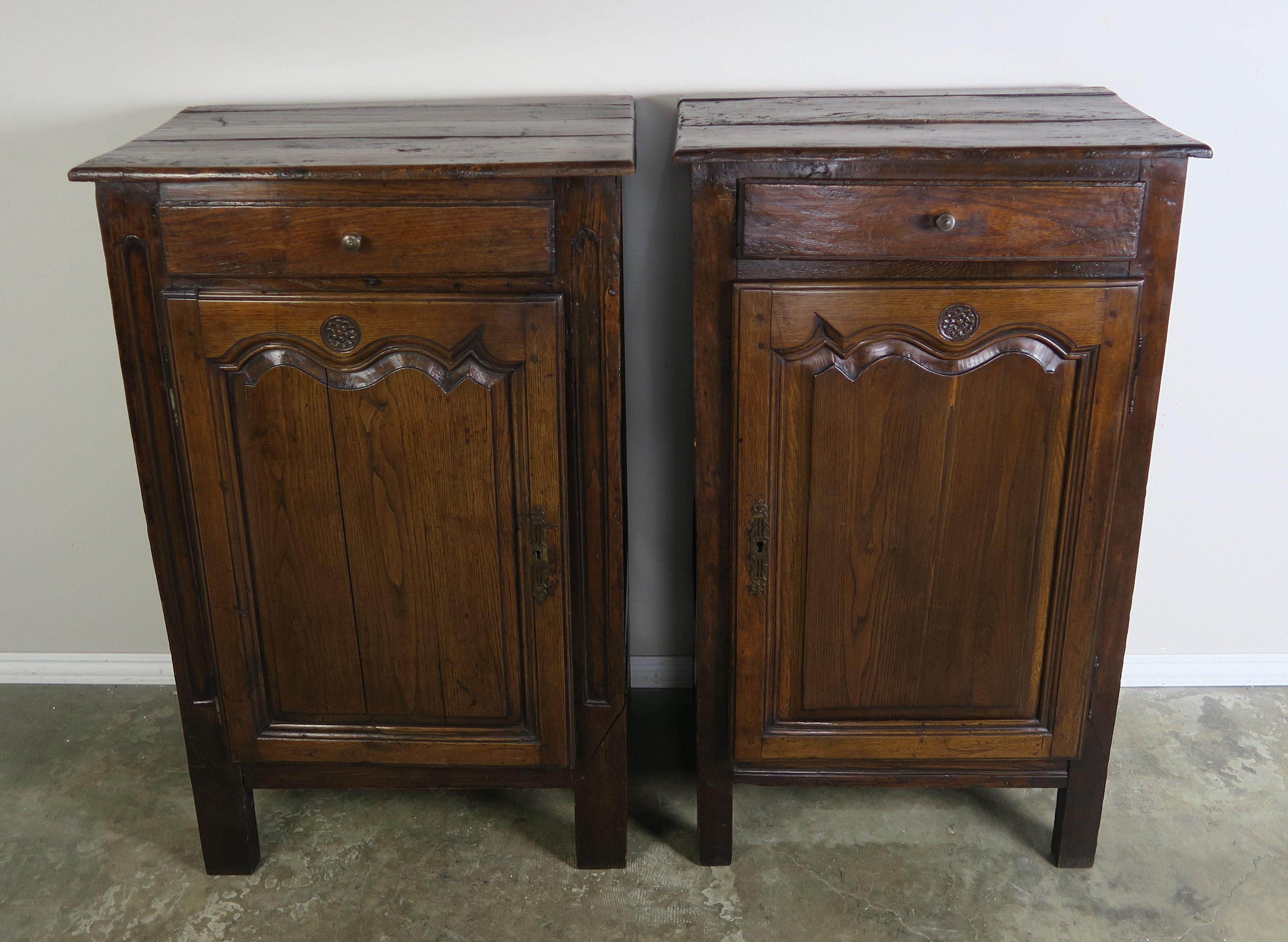 Pair of 19th century French Provincial style walnut cabinets with original brass hardware. Each cabinet has a drawer and paneled door that hides two shelves. Great storage pieces.
