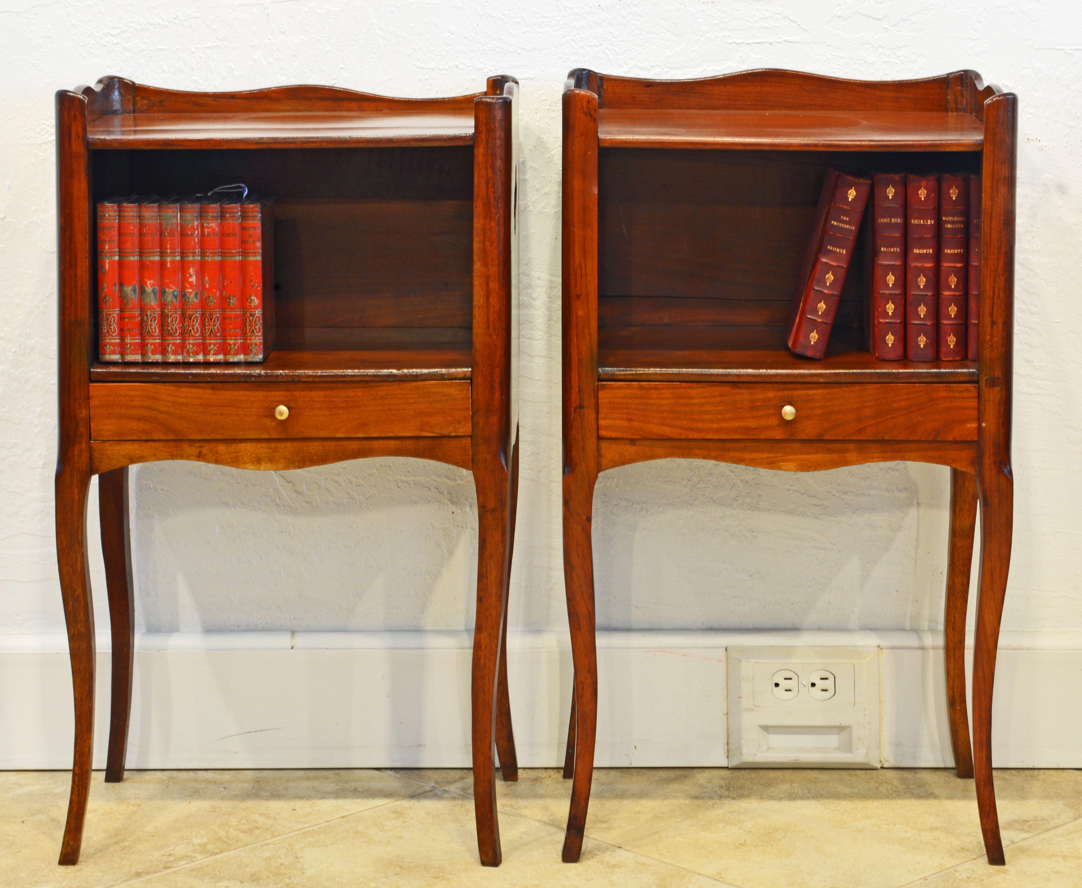 This pair of French Provincial tables or stands feature polished tops surrounded on three sides by scalloped edges above open compartments over drawers and resting on elegant cabriole legs. A charming detail are the clover shape cutouts in both