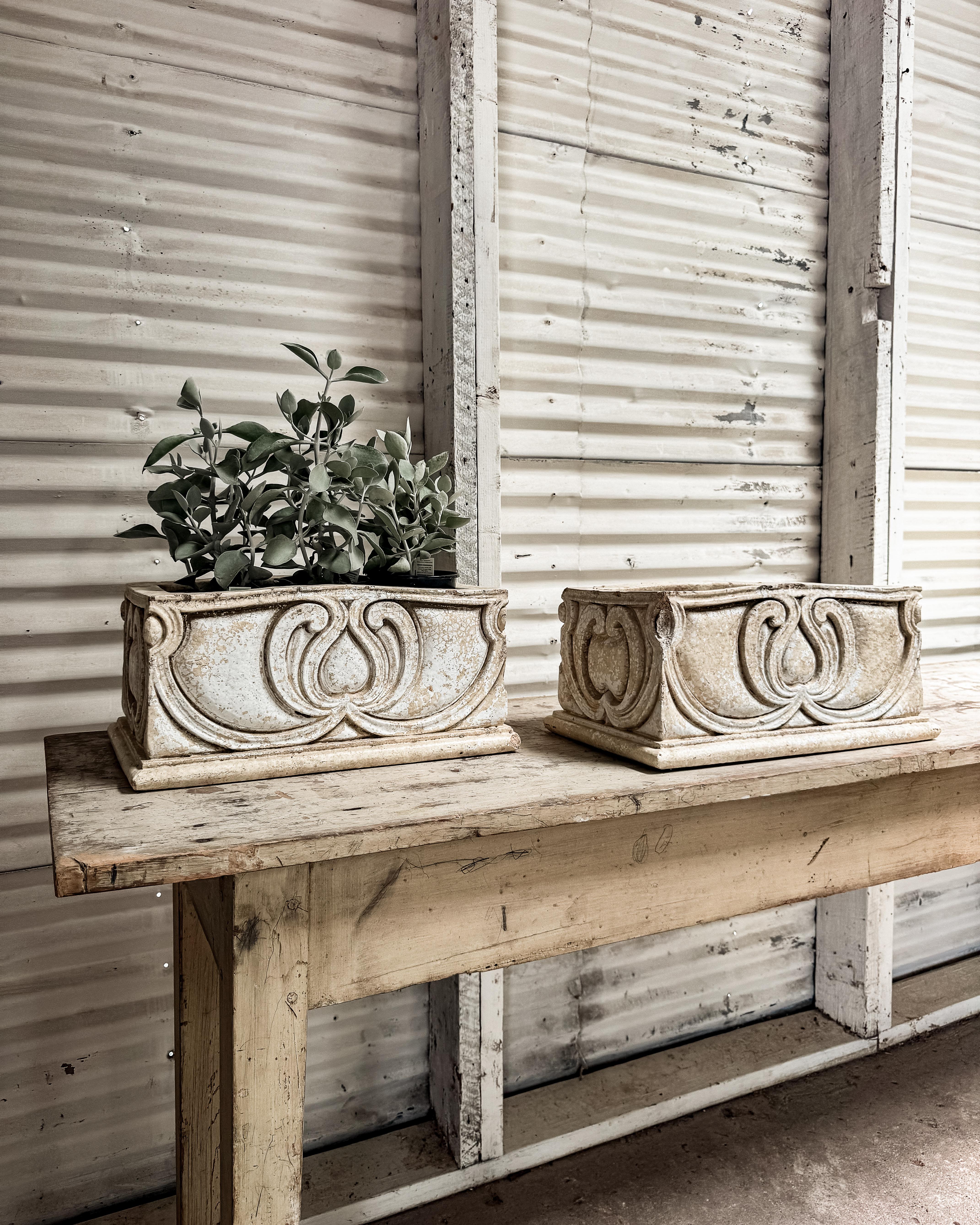 Discovered in France and dating to the 19th century, this pair of rectangular planters brings an elegant touch to any garden or interior. Crafted from thick ceramic with a glazed finish, they feature an ornate raised design on all four sides,