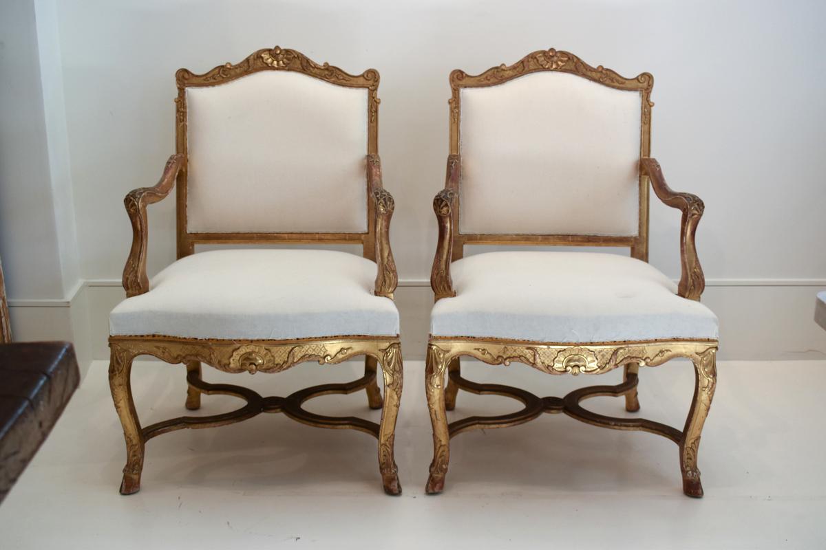 Cette exquise paire de fauteuils de la Régence française du XIXe siècle respire l'élégance et la sophistication, caractéristiques de la période de la Régence. Chaque fauteuil est doté d'un cadre en bois doré minutieusement sculpté et orné de détails