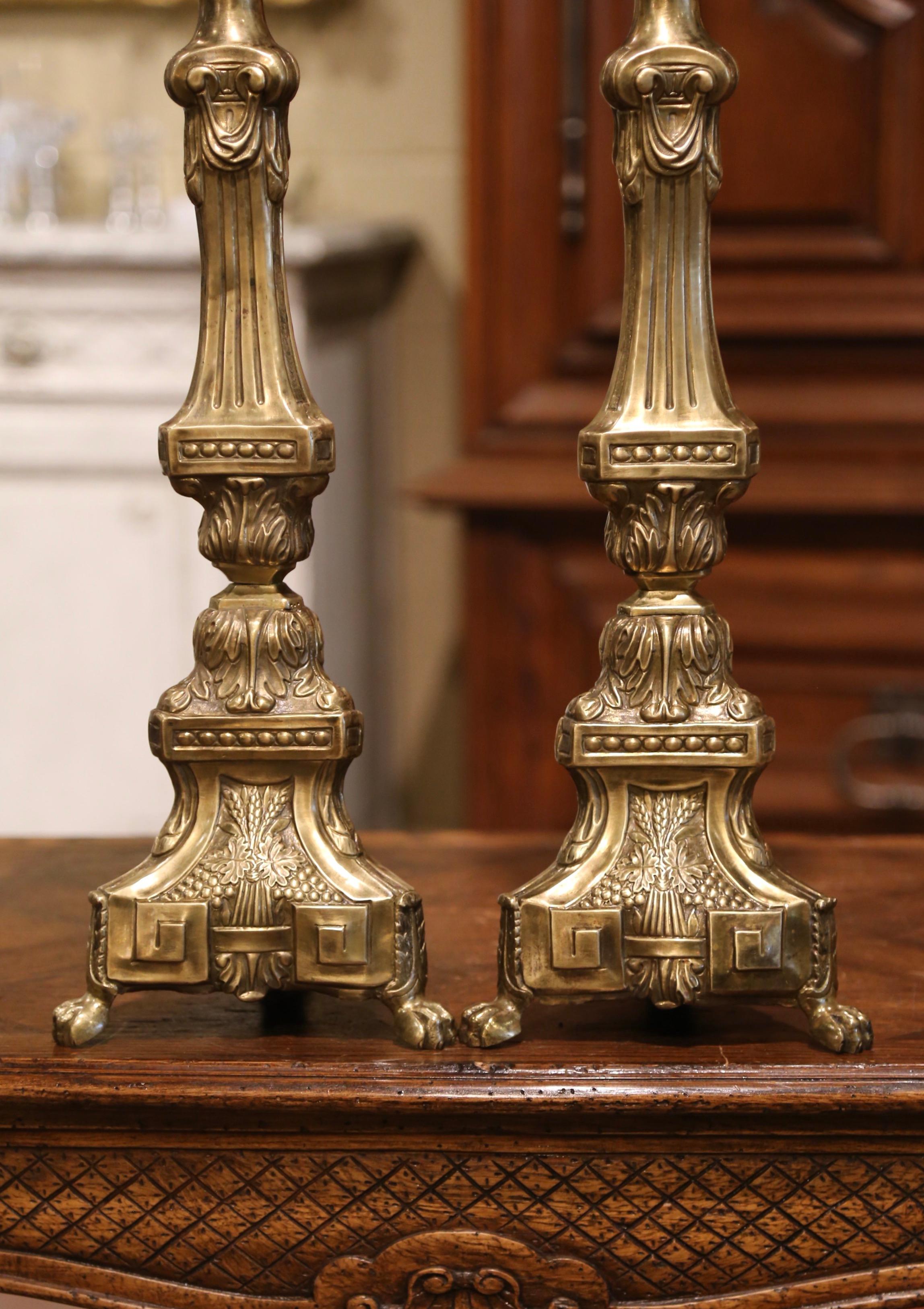 These brass candlesticks were found in a private chapel near Lyon, France. Crafted circa 1860, each candlestick sits on small paw feet with three sides decorated by repousse catholic motifs: the lamb, wheat for the bread and wine for the blood. The