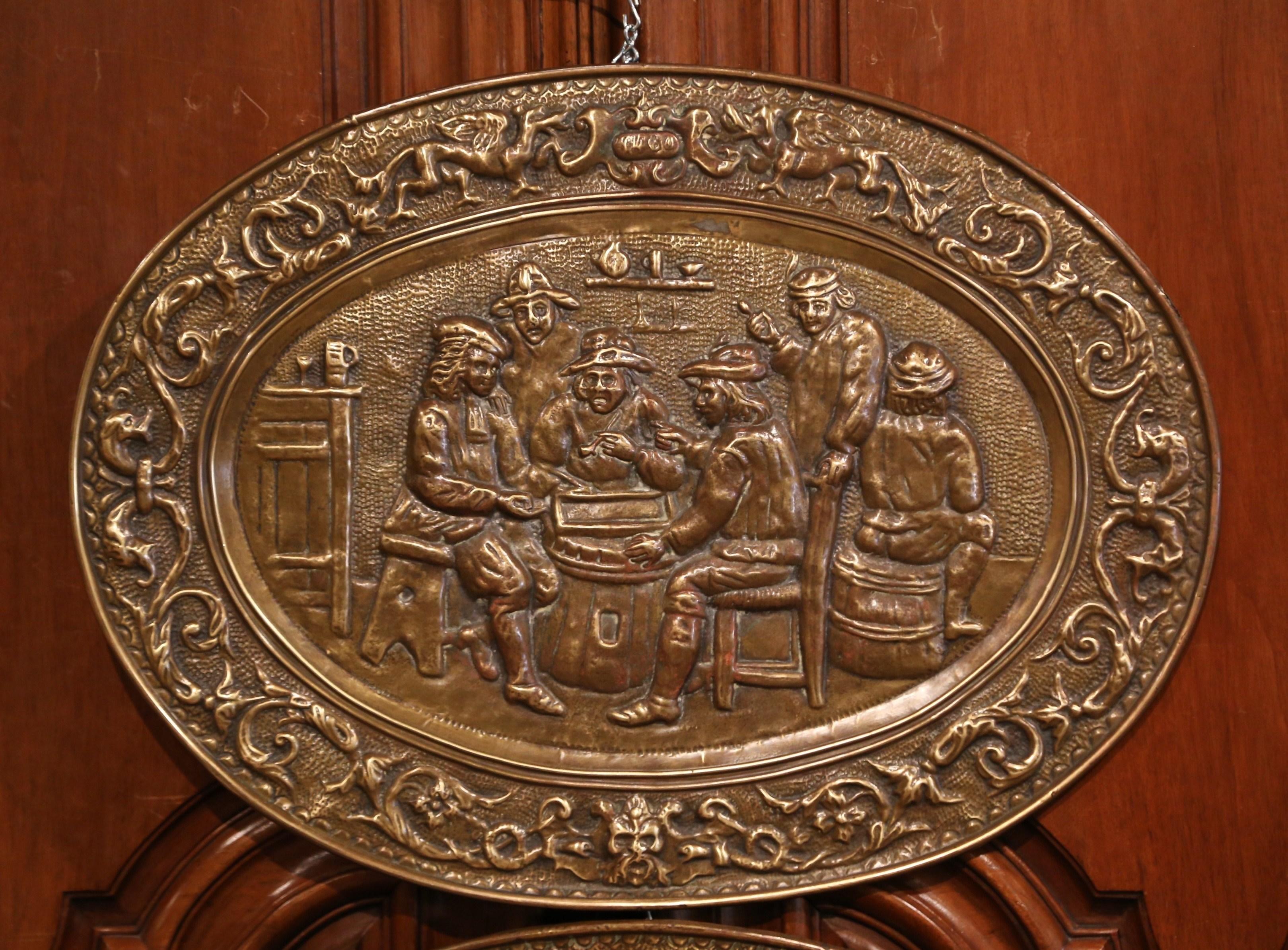 These antique plaques were created in France, circa 1880. Oval in shape and made of repousse copper, each plaque depicts a cabaret scene in the manner of David Teniers with people drinking and playing cards. The wall decorations are in excellent