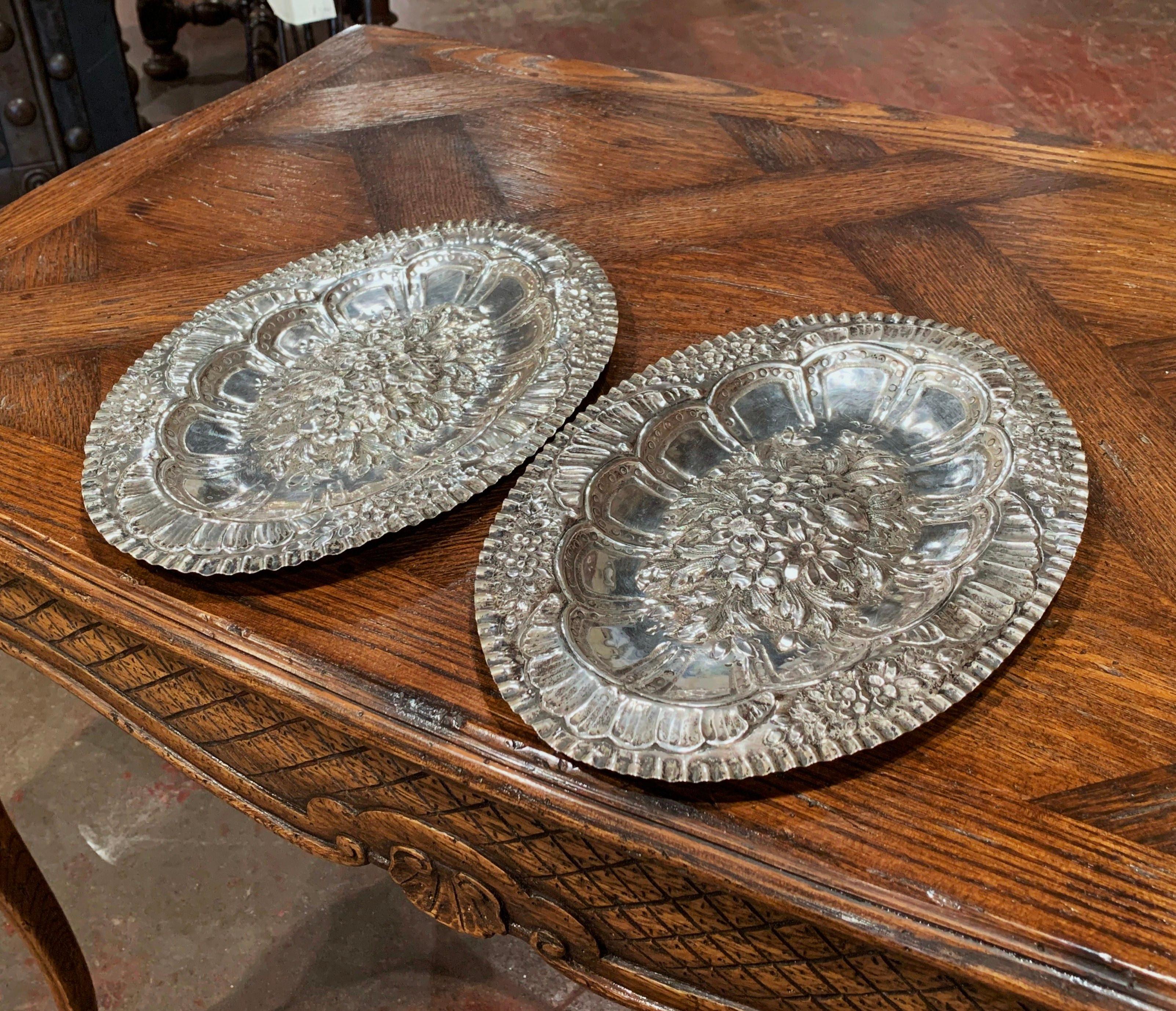 Decorate a wall or a shelf with this pair of highly detailed, antique wall plaques. Crafted in France circa 1880, each oval plaque features a large repousse floral medallion in the center, and is embellished with leaf and floral decor around the