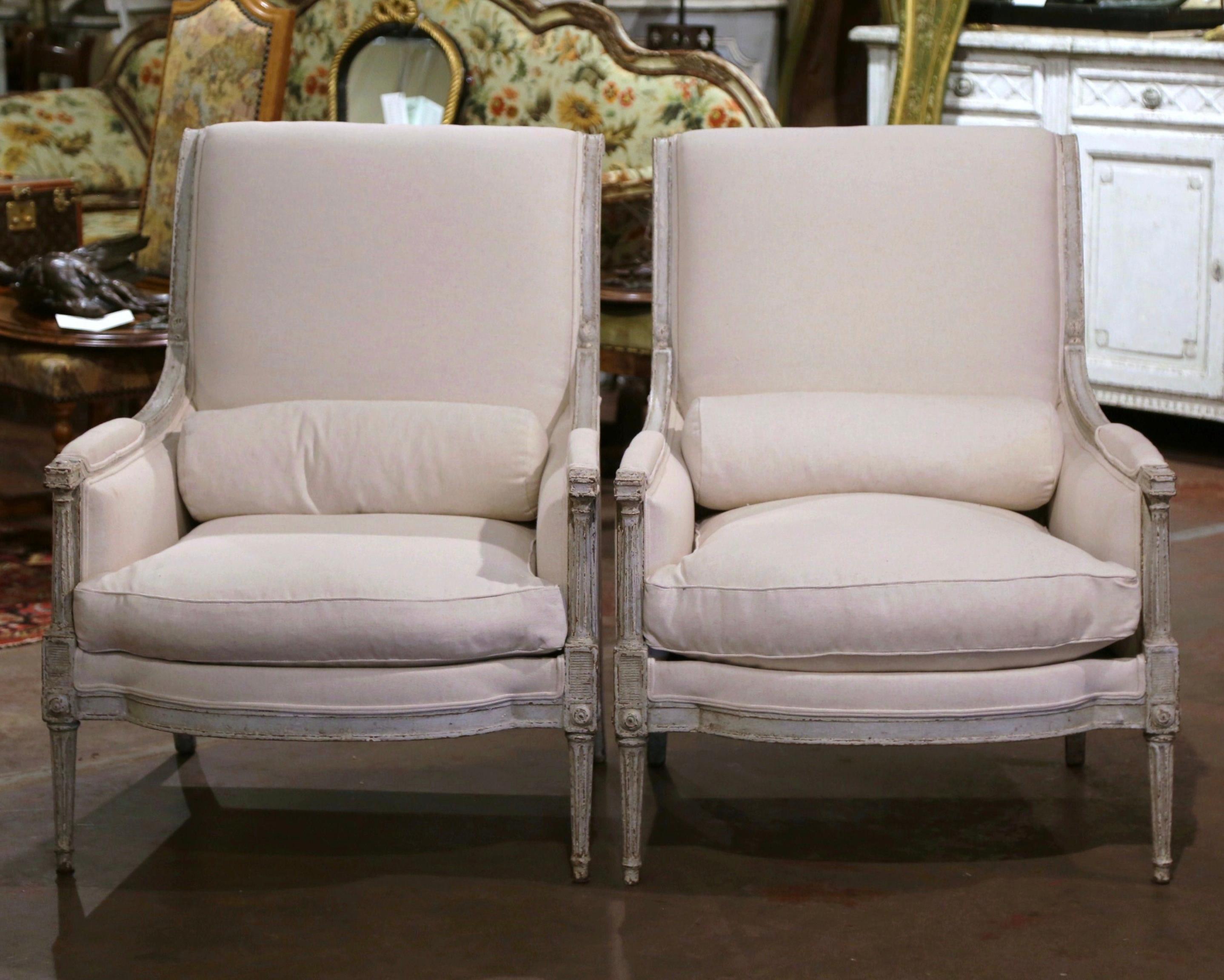 This elegant pair of antique armchairs was created in France, circa 1880. The large fauteuils with tall and rolled back, stand on tapered and fluted front legs decorated with square medallions at the shoulders over a bombe apron, and curved back