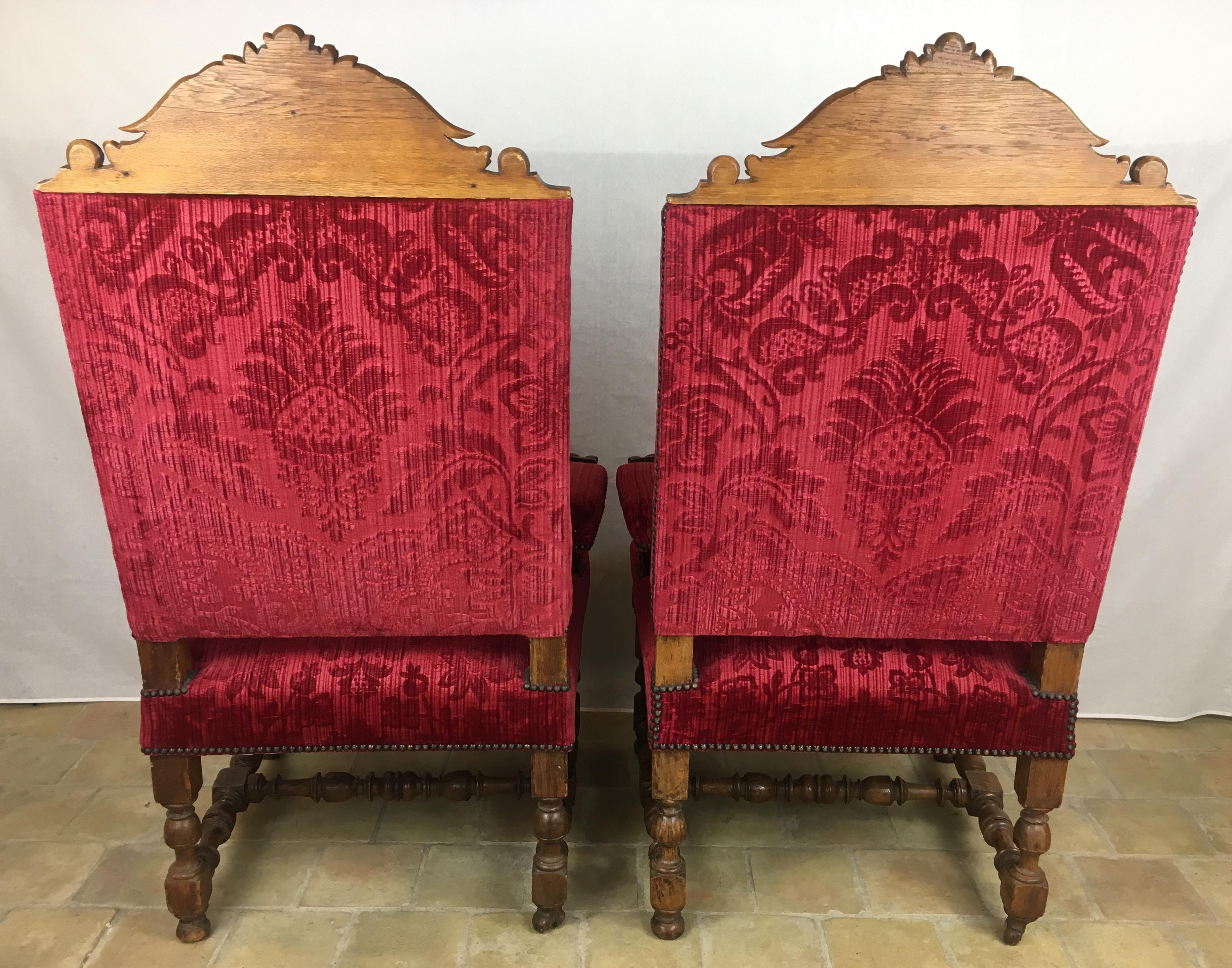 Pair of French 19th century Revival Louis XIII style throne armchairs with hand carved figures on the raised arm rests and top of the chair backs. 

These quality throne armchairs feature high slanted backs, the velvet upholstery contrasts nicely