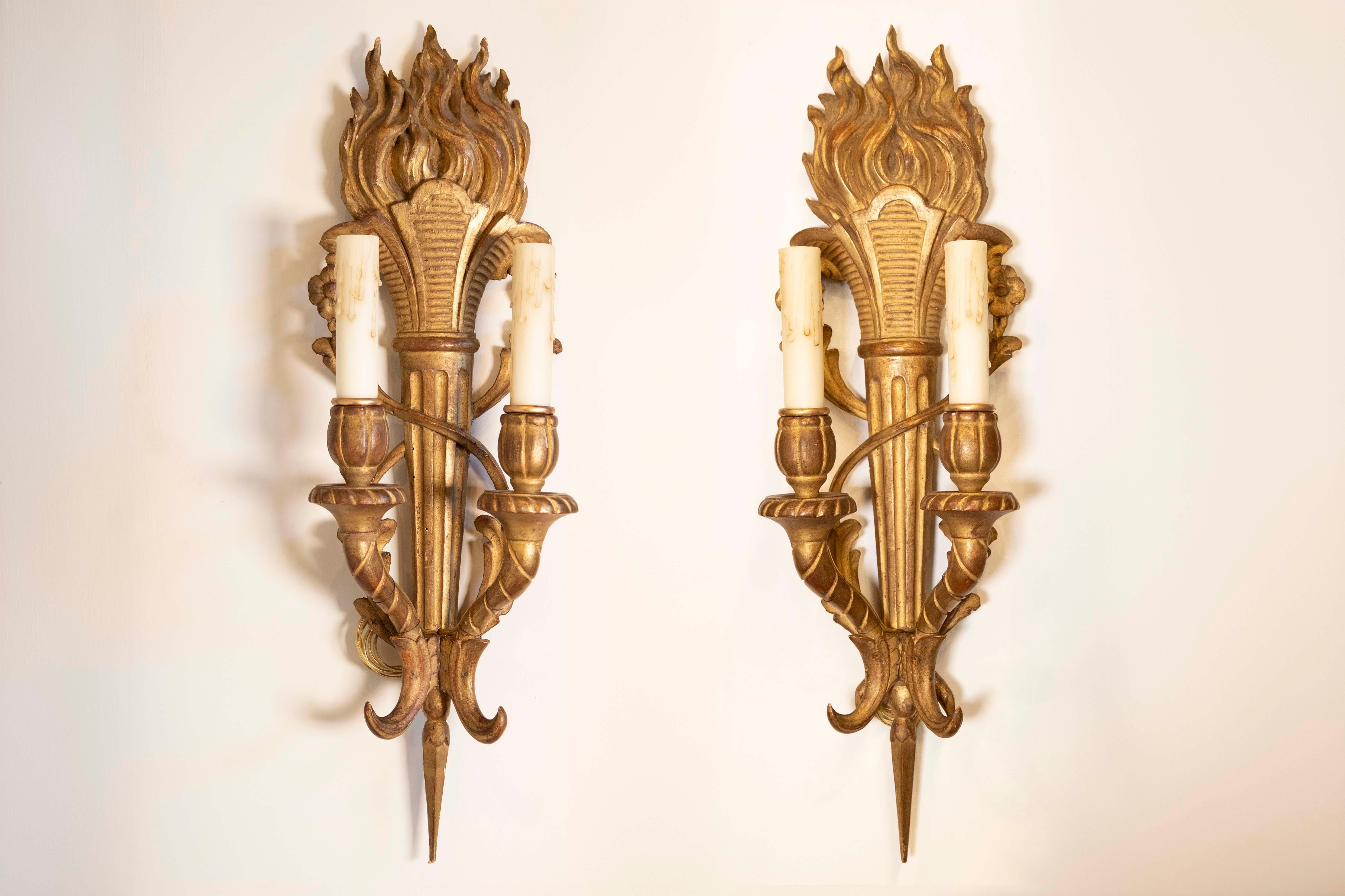 Questa splendida coppia di applique francesi del XIX secolo incarna la grandezza e la maestria dello stile Luigi XVI. Realizzate con maestria in legno dorato, queste appliques sono disegnate con un elegante motivo a torcia, che simboleggia