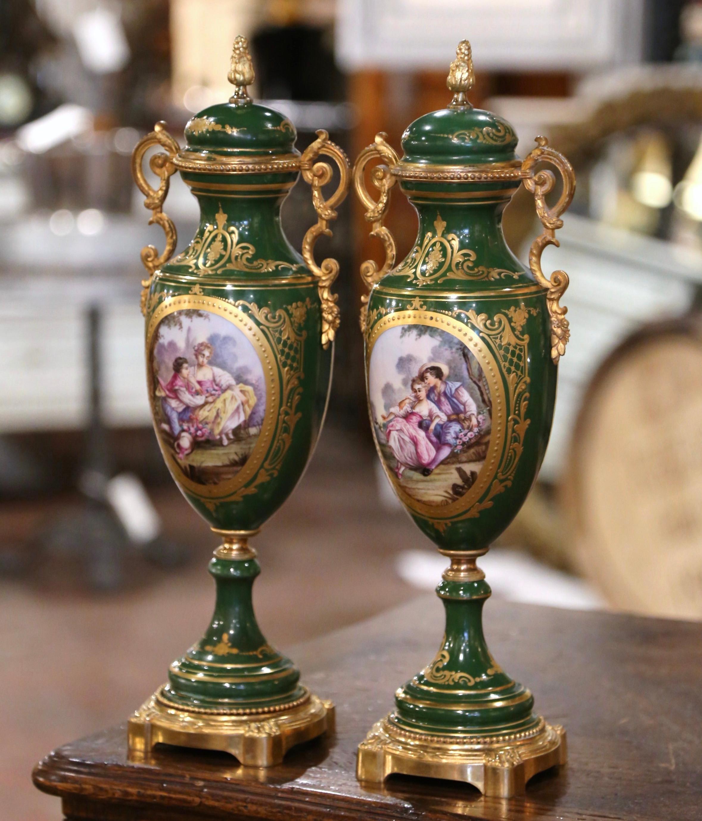 Decorate a mantel or a console with this elegant pair of porcelain and gilt metal Sèvres urns. Created in Paris, France, circa 1880, each colorful vase sits on a round gilt base decorated with acanthus leaf motifs over the feet. Each urn is