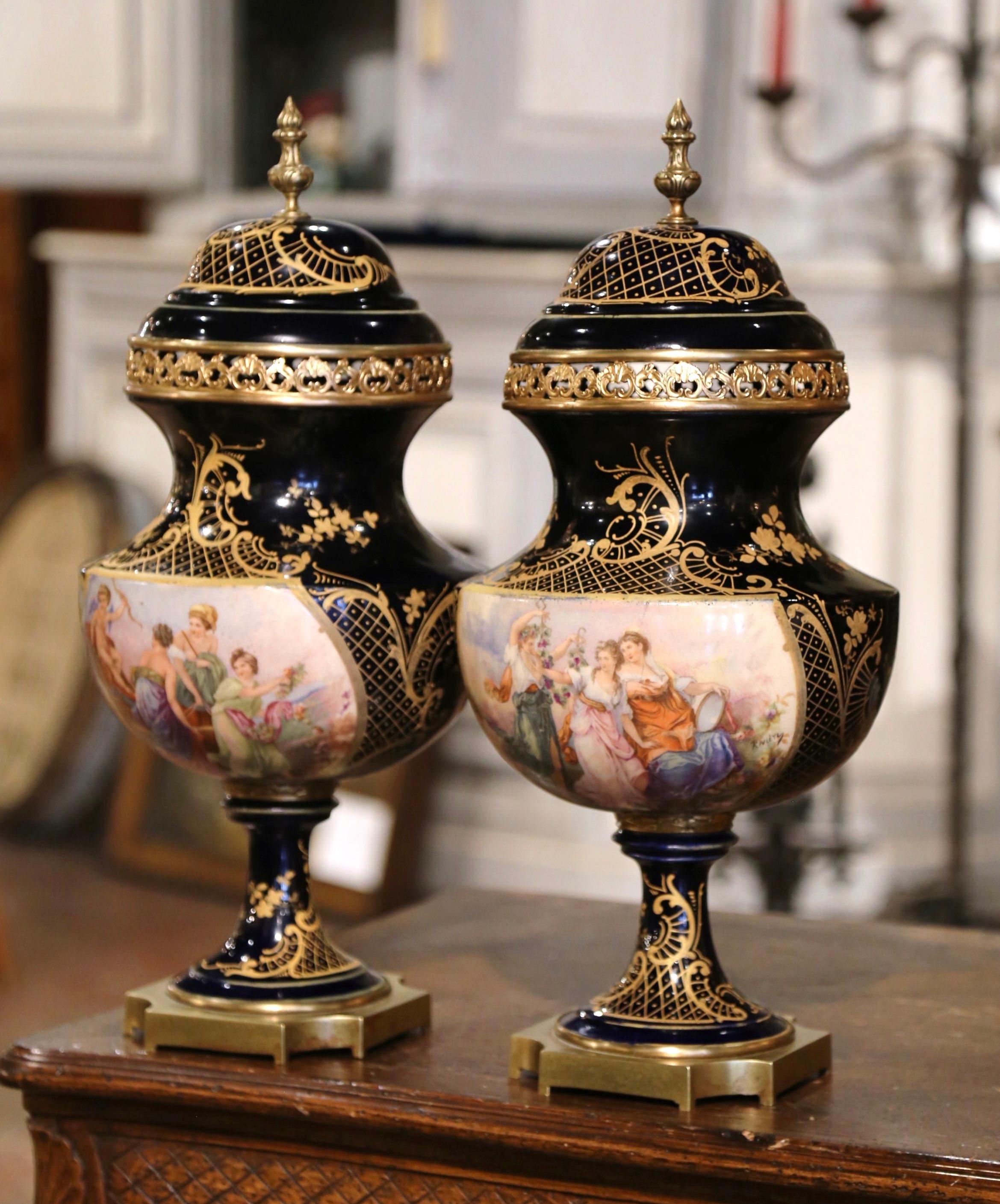 Decorate a mantel or a console with this important pair of antique Sèvres urns. Created in Paris, France circa 1890, each elegant vase sits on a square gilt bronze base with cut corners. The large porcelain vase is decorated with a hand painted