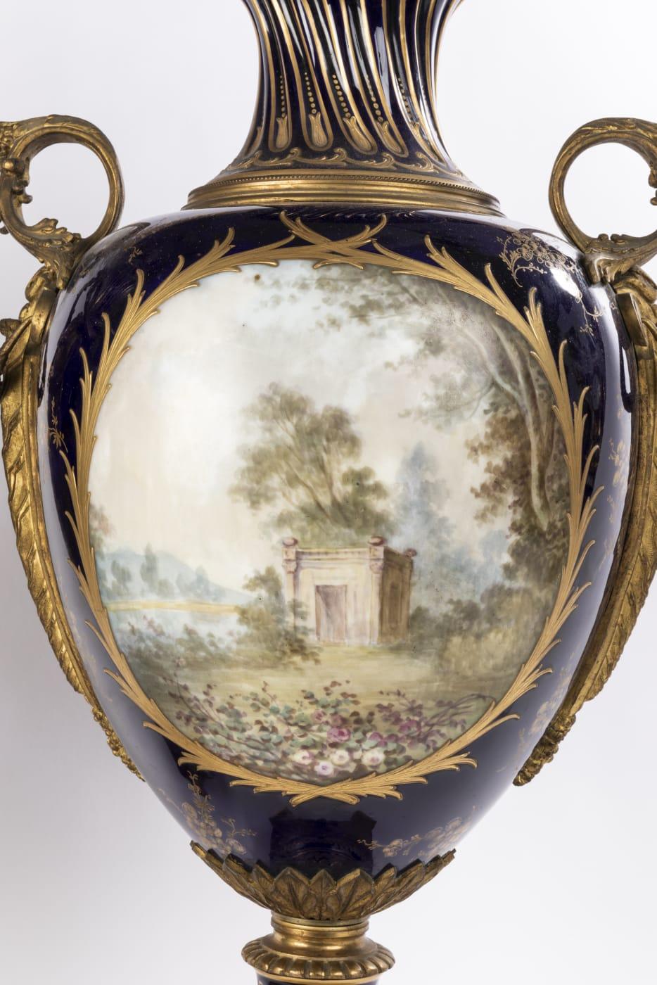 Two large and impressive 19th century French Sevres style porcelain vases have a fascinating dark blue background. Each vase is placed on an octagonal base adorned with intricate designs. The front panel on each is hand painted to represent a